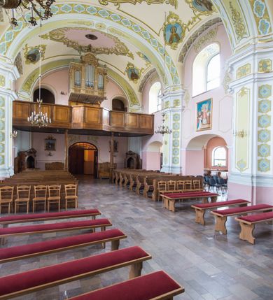 Zdjęcie nr 10: Orientowany kościół św. Wojciecha w Bulowicach obecnie uzyskał strukturę trójnawowej, trójprzęsłowej bazyliki z jednoprzęsłowym, nieco węższym prezbiterium zamkniętym spłaszczoną absydą. Na przedłużeniu dostawionych naw wybudowano półkolisty aneks zakrystyjny okalający apsydę, przepruwając go trzema półokrągłymi oknami oraz wejściem na osi. W aneksie od strony południowo-wschodniej urządzono otwartą na zewnątrz półkolistą arkadą kaplicę Ogrójcową. Od zachodu do nawy głównej przylega lekko wysunięta do przodu czworoboczna wieża flankowana dwoma, piętrowymi aneksami. Elewację masywu wieżowego artykułuje profilowany gzyms koronujący wyłamany na szerokości wieży, podtrzymujący miedziany daszek pulpitowy, dzielący ją na dwie kondygnacje. Podobny gzyms zamyka wieżę u góry, ponad którym wznosi się cebulasty hełm zwieńczony krzyżem na bani. Pod gzymsem w górnej części wieży usytuowano tarcze zegarowe oraz poniżej półokrągłe okna. W jej przyziemiu urządzono kruchtę, do której prowadzi portal uszaty z widocznym nad nim odcinkiem belkowania. Za pomocą symetrycznych spływów dostawione dwie nawy zostały połączone w spójną całość z masywem wieżowym. Do obu naw prowadzą półokrągłe arkady, w których urządzono otwarte przedsionki poprzedzające weście do kościoła. Nawę główną i prezbiterium nakryto dachem siodłowym. W jej części wschodniej nadwieszono wieżyczkę na sygnaturkę w kształcie sześciobocznej latarnii z baniastym hełmem i krzyżem. Nawy boczne i aneks zakrystyjny przykryto dachami pulpitowymi. Elewacje zewnętrzne zostały pozbawione artykulacji za wyjątkiem niskiego kamiennego cokołu obiegającego całą świątynię. Wnętrze nawy głównej zostało rozczłonkowane za pomocą opilastrowanych filarów, ponad którymi widoczne są odcinki belkowania. W tęczy kościoła zastosowano pilastry zdwojone. Nawy boczne połączono z nawą główną za pomocą mocno spłaszczonych arkad. Ponad nimi przepruto prostokątne okna zamknięte łukiem odcinkowym. Całość nawy nakryto sklepieniem żagielkowym wspartym na gurtach, zaś prezbiterium przykryto hemisferycznie. W części zachodniej nawy głównej zawieszono chór muzyczny wsparty na dwóch drewnianych filarach z drewnianym, pełnym parapetem artykułowanym czworobocznymi płycinami. Na osi środkowej parapet wyłamano na rzucie trapezu. W prezbiterium ustawiono ołtarz główny, a przy łuku tęczowym dwa ołtarze boczne. Na północnej ścianie łuku tęczowego zawieszono ambonę. Dwa niewielkie ołtarze boczne znalazły się także na zakończeniu naw bocznych.   