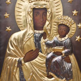 Zdjęcie nr 1: Obraz uzyskał kształt stojącego prostokąta. W centrum kompozycji na ciemny tle rozjaśnionym nieznacznie wokół postaci wyobrażono Matkę Boską z Dzieciątkiem w typie Częstochowskim. Obie postacie przykrywają złocone i srebrzone sukienki wotywne oraz korony, odsłaniające partię twarzy, dłoni oraz stopy Dzieciątka. Madonna została ukazana frontalnie w półpostaci. Prawą ręką wskazuje na trzymane na lewym ramieniu Dzieciątko Jezus. Jej podłużną twarz o ciemnej karnacji charakteryzuje wydatny, prosty nos, migdałowe oczy, mięsiste usta oraz dwa równoległe cięcia widoczne na prawym policzku. Na głowie ma złocony maforion lamowany taśmą z imitacją kameryzacji, odsłaniający fragment srebrzonej sukni lamowanej podobną taśmą co maforion pod szyją. Maryja ma na głowie złoconą koronę o wysokich, stylizowanych sterczynach dekorowaną imitacją srebrzonych kamieni szlachetnych. Dzieciątko zostało ujęte w trzech czwartych w lewo. Prawą rękę wznosi w geście błogosławieństwa, w lewej natomiast trzyma gruby kodeks. Mały Jezus ma owalną twarz o ciemnej karnacji. Widoczny jest wydatny nos i usta oraz szeroko otwarte oczy. Ma na sobie srebrzoną tunikę lamowaną złoconą taśmą i zdobioną naśladowaniem kameryzacji. Głowę Chrystusa wieńczy korona, kształtem i dekoracją zbliżona do korony Madonny. Głowy postaci otaczają złociste, zębate nimby. Okala je ponadto otok ze złotymi gwiazdami przytwierdzonymi do podłoża jako aplikacje.