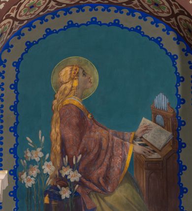 Zdjęcie nr 6: W prezbiterium w absydzie do dwóch trzecich wysokości ściany dekoracja roślinno-geometryczna z motywami kwiatowymi w kolorach zielono-turkusowym oraz złotym; powyżej dwa anioły na tle niebieskiego nieba z rozetami, całość zakończona zgeometryzowaną glorią promienistą uzupełnioną motywami kwiatowymi. 
Ściany boczne prezbiterium w kolorze jasnego różu; na ścianie tarczowej południowej medalion z kielichem i hostią w glorii promienistej. Na pilastrach, gurtach sklepiennych i w rozglifieniach okien symetryczna dekoracja roślinna. Na sklepieniu jasnopomarańczowe pole, w którego centrum znajduje się medalion z przedstawieniem Veraicon w glorii promienistej uzupełnionej motywami roślinnymi. 
Łuk tęczowy pokryty ornamentem roślinnym z motywami kłosów zbóż, na niebieskim tle, na środku łuku przedstawienie pelikana w gnieździe. Po wewnętrznej stronie łuku malatura w postaci fantazyjnego ornamentu roślinnego na beżowym tle. 
Ściany nawy gładkie, w kolorze zgaszonej, jasnej zieleni; z malowanymi zacheuszkami. W rozglifieniach okien symetryczna, stylizowana dekoracja arabeskowa na pomarańczowym i żółtym tle. Pilastry i łuki pokryte różnokolorowym, fantazyjnym ornamentem roślinnym. Sklepienia w każdym przęśle z wydzielonymi jasnożółtymi, owalnymi polami, w których centrum znajdują się niebieskie medaliony z przedstawieniem gorejącego serca lub monogramu IHS, w koronie cierniowej, w wieńcu z dekoracji roślinnej i w fioletowej glorii promienistej. W przyłuczach sklepień medaliony z przedstawieniami popiersi 12 apostołów, po czterech w każdym przęśle, ujętych żółtą wicią roślinną, na zielonym tle. Gurty sklepienne z motywem krzyży na żółto-pomarańczowym tle. 
Parapet chóru muzycznego i wspierające go arkady podzielone na malowane pola i płyciny wypełnione fantazyjnym ornamentem roślinnym. Na osi balustrady chóru przedstawienie liry. W podłuczu środkowej arkady pod chórem oko Opatrzności w wielobarwnej, stylizowanej glorii promienistej. 
Na ścianie zachodniej dwie półkoliście zamknięte nisze z przedstawieniami z lewej strony św. Cecylii grającej na organach, zaś z prawej króla Dawida grającego na harfie, na jasnoniebieskim tle. W rozglifieniach nisz stylizowana dekoracja geometryczno-roślinna. 
