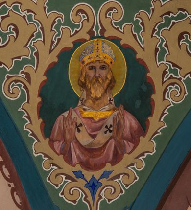 Zdjęcie nr 5: W prezbiterium w absydzie do dwóch trzecich wysokości ściany dekoracja roślinno-geometryczna z motywami kwiatowymi w kolorach zielono-turkusowym oraz złotym; powyżej dwa anioły na tle niebieskiego nieba z rozetami, całość zakończona zgeometryzowaną glorią promienistą uzupełnioną motywami kwiatowymi. 
Ściany boczne prezbiterium w kolorze jasnego różu; na ścianie tarczowej południowej medalion z kielichem i hostią w glorii promienistej. Na pilastrach, gurtach sklepiennych i w rozglifieniach okien symetryczna dekoracja roślinna. Na sklepieniu jasnopomarańczowe pole, w którego centrum znajduje się medalion z przedstawieniem Veraicon w glorii promienistej uzupełnionej motywami roślinnymi. 
Łuk tęczowy pokryty ornamentem roślinnym z motywami kłosów zbóż, na niebieskim tle, na środku łuku przedstawienie pelikana w gnieździe. Po wewnętrznej stronie łuku malatura w postaci fantazyjnego ornamentu roślinnego na beżowym tle. 
Ściany nawy gładkie, w kolorze zgaszonej, jasnej zieleni; z malowanymi zacheuszkami. W rozglifieniach okien symetryczna, stylizowana dekoracja arabeskowa na pomarańczowym i żółtym tle. Pilastry i łuki pokryte różnokolorowym, fantazyjnym ornamentem roślinnym. Sklepienia w każdym przęśle z wydzielonymi jasnożółtymi, owalnymi polami, w których centrum znajdują się niebieskie medaliony z przedstawieniem gorejącego serca lub monogramu IHS, w koronie cierniowej, w wieńcu z dekoracji roślinnej i w fioletowej glorii promienistej. W przyłuczach sklepień medaliony z przedstawieniami popiersi 12 apostołów, po czterech w każdym przęśle, ujętych żółtą wicią roślinną, na zielonym tle. Gurty sklepienne z motywem krzyży na żółto-pomarańczowym tle. 
Parapet chóru muzycznego i wspierające go arkady podzielone na malowane pola i płyciny wypełnione fantazyjnym ornamentem roślinnym. Na osi balustrady chóru przedstawienie liry. W podłuczu środkowej arkady pod chórem oko Opatrzności w wielobarwnej, stylizowanej glorii promienistej. 
Na ścianie zachodniej dwie półkoliście zamknięte nisze z przedstawieniami z lewej strony św. Cecylii grającej na organach, zaś z prawej króla Dawida grającego na harfie, na jasnoniebieskim tle. W rozglifieniach nisz stylizowana dekoracja geometryczno-roślinna. 
