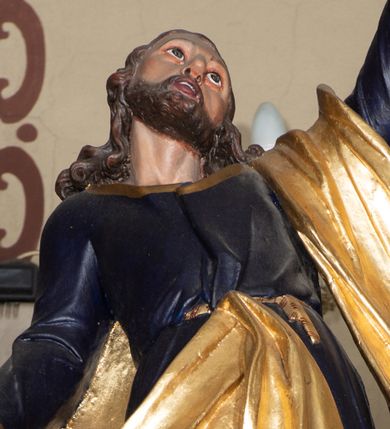 Zdjęcie nr 1: Rzeźba pełna, ustawiona na niskiej podstawie. Święty zwrócony frontalnie, odchylony, z głową skierowaną w górę, w wykroku. Lewą rękę unosi wysoko w górę, prawą w bok, w dłoni trzyma klucze. Twarz ma szczupłą, o dużych oczach skierowanych w górę, garbatym nosie oraz pełnych, otwartych ustach; okoloną krótką, kręconą brodą oraz kręconymi włosami, sięgającymi ramion. Święty ubrany w ciemnoniebieską tunikę ze złoconymi lamówkami, przepasaną w talii oraz złocony płaszcz zarzucony na lewe przedramię i zawiązany w pasie z przodu postaci. Na stopach ma sandały. Polichromia ciała naturalistyczna.
