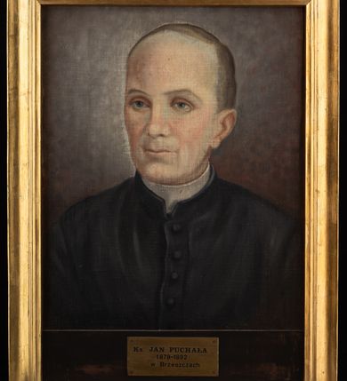 Zdjęcie nr 2: Portret uzyskał kształt stojącego prostokąta ujętego w złoconą, profilowaną ramę. Na ciemnym tle rozjaśnionym wokoło głowy przedstawiono w popiersiu duchownego ujętego w trzech czwartych w lewo. Jest to dojrzały mężczyzna z pociągłą twarzą z bardzo wysokim, łysym czołem z krótkimi włosami zaczesanymi w niewielką grzywkę i odsłaniającymi lewe ucho. Jego twarz charakteryzuje jasna karnacja, wydatny nos, wąskie usta i niebieskie oczy. Ubrany jest w czarną sutannę z białą koloratką pod szyją.  