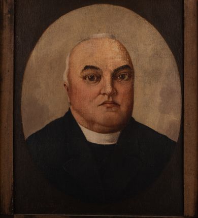 Zdjęcie nr 1: Portret uzyskał kształt stojącego prostokąta ujętego w złoconą, profilowaną ramę. W prostokąt wpisano wydłużony owal, w którym na jasnym tle przedstawiono w popiersiu duchownego nieznacznie ujętego w trzech czwartych w lewo. Jest to dojrzały mężczyzna z pociągłą twarzą, wysokim, łysym czołem, z krótkimi, siwiejącymi włosami zaczesanymi do tyłu. Jego owalną twarz charakteryzują jasna karnacja, mięsisty nos, wydatne usta oraz szeroko otwarte brązowe oczy ze spojrzeniem skierowanym w stronę widza. Fragmentarycznie widoczne jest jego prawo ucho. Ubrany jest w surdut z widoczną pod szyją białą koloratką. Pod portretem umieszczono tabliczkę z napisem "Ks(iądz) prob(oszcz) Julian Migdałek / 1904-1925 / w Brzeszczach".