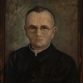 Zdjęcie nr 1: Portret uzyskał kształt stojącego prostokąta ujętego w złoconą, profilowaną ramę. Na ciemnym tle nieznacznie rozjaśnionym wokoło głowy przedstawiono w popiersiu duchownego nieznacznie ujętego w trzech czwartych w lewo. Jest to dojrzały mężczyzna w okrągłych okularach o złocistych oprawkach z pociągłą twarzą, bardzo wysokim czołem, z krótkimi, szpakowatymi włosami zaczesanymi do tyłu. Jego twarz charakteryzują jasna karnacja, wydatny nos, wąskie usta, ciemne oczy i krzaczaste brwi. Widoczne są także uszy. Ubrany jest w czarną sutannę z białą koloratką pod szyją. Pod portretem znajduje się tabliczka z napisem "Ks(iądz) prob(oszcz) / STANISŁAW KUCHARCZYK / 1925-1932 / w Brzeszczach".  