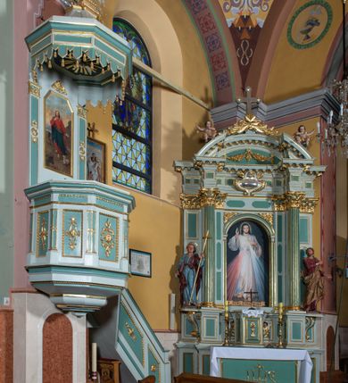 Zdjęcie nr 3: Przyścienna, wisząca ambona składa się z kosza i prowadzących do niego jednobiegowych schodów z balustradą, zaplecka oraz baldachimu. Wieloboczny kosz ustawiono na profilowanym, łamanym cokole. Poniżej widoczne jest podwieszenie utworzone ze zmniejszających się profilów układających się w spłaszczony stożek. Boki kosza artykułowano za pomocą diagonalnie ustawionych filarków na cokolikach podtrzymujących imposty z profilowanym i łamanym belkowaniem. Trzony filarków ozdobiono prostokątnymi płycinami z rozetą w środku. Płaszczyzny pomiędzy filarkami udekorowano prostokątnymi płycinami obwiedzionymi obramieniami z wolich oczu z geometryzowanym, płaskorzeźbionym ornamentem roślinno-kwiatowym w polu. Płyciny pomiędzy impostami przy górnych krawędziach ozdobiono ornamentem kostkowym. Zaplecek ambony ujęto dwoma pilastrami o płaskich głowicach zdobionych motywem stylizowanych liści.  Trzony pilastrów przedzielono na środku medalionem z rozetą i dwiema palmetami. Pomiędzy pilastrami umieszczono pole obrazowe w kształcie wydłużonego prostokąta o ściętych narożach w części górnej. W polu znajduje się obraz z całopostaciowym przedstawieniem Chrystusa jako Dobrego Pasterza. Ponad zapleckiem zawieszono wieloboczny baldachim utworzony z łamanego, profilowanego belkowania i podwieszonego lambrekinu, zwieńczony wielobocznymi spływami, na szczycie których  umieszczono na poduszce zamkniętą księgę, a za nią na obłokach w otoczeniu promieni dwie tablice Dekalogu. Strukturę architektoniczną ambony polichromowano w kolorze opalizującej zieleni, profile, ornamenty wyzłocona, a tablice Dekalogu i obłoki posrebrzono.     