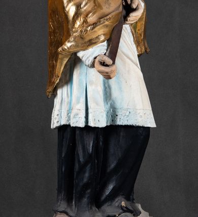 Zdjęcie nr 3: Feretron składa się z całopostaciowej rzeźby św. Jana Nepomucena ustawionej na niskim czworobocznym postumencie przymocowanym do rozbudowanego, profilowanego cokołu przeprutego w osiach skrajnych otworami na drążki do noszenia. Jan Nepomucen został ukazany frontalnie w nieznacznym kontrapoście. Na lewym przedramieniu trzyma krucyfiks z pasyjką od dołu wsparty prawą ręką. Święty ma owalną twarz z jasną karnacją o pełnych, rumianych policzkach, wydatnym nosie i ustach i szeroko otwartych oczach o spojrzeniu skierowanym na widza. Jego głowę otaczają krótkie, brązowe włosy widoczne spod biretu, który ma na głowie oraz krótka broda. Kapłan ubrany jest w czarną sutannę z parterami, białą komżę  dekorowaną u spodu koronką oraz pozłoconą almucję. 