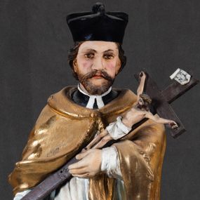 Zdjęcie nr 1: Feretron składa się z całopostaciowej rzeźby św. Jana Nepomucena ustawionej na niskim czworobocznym postumencie przymocowanym do rozbudowanego, profilowanego cokołu przeprutego w osiach skrajnych otworami na drążki do noszenia. Jan Nepomucen został ukazany frontalnie w nieznacznym kontrapoście. Na lewym przedramieniu trzyma krucyfiks z pasyjką od dołu wsparty prawą ręką. Święty ma owalną twarz z jasną karnacją o pełnych, rumianych policzkach, wydatnym nosie i ustach i szeroko otwartych oczach o spojrzeniu skierowanym na widza. Jego głowę otaczają krótkie, brązowe włosy widoczne spod biretu, który ma na głowie oraz krótka broda. Kapłan ubrany jest w czarną sutannę z parterami, białą komżę  dekorowaną u spodu koronką oraz pozłoconą almucję. 