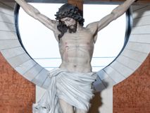 Zdjęcie nr 1: Na krzyżu z jasnego drewna zawieszono polichromowaną figurę martwego Chrystusa o szeroko rozpostartych ramionach. Ciało Zbawiciela do krzyża jest przymocowane za pomocą trzech gwoździ. On sam został ukazany jako martwy z zamkniętymi oczami i nieznacznie słaniającą się głową. Jego postać jest nieznacznie wysmuklona z naturalnie potraktowaną muskulaturą korpusu, zaznaczononą raną prawego boku. Nogi są lekko zwrółcone do osi środkowej, z założeniem prawej stopy na lewą. Twarz Zbawiciela jest mocno wychudła i pociągła. Charakteryzują ją zamknięte oczy, wydatny nos i usta. Otaczają ją brązowe włosy opadające puklami na kark oraz na prawe ramię oraz  brązowy zarost. Chrystus ma na głowie cierniową koronę, spod której na czoło spływają nieznaczne krople krwi. Biodra Zbawiciela przepasane są szarobiałym perizonium w formie zawoju z rozwianym festonem przy prawym boku. Tkaninę drapują ostre załamania. Ponad głową Chrystusa na pionowej belce krzyża zawieszono rozwiany titulus z napisem INRI przytwierdzone do krzyża wbitym na środku gwoździem. Całą figurę pokrywa naturalistyczna polichromia.