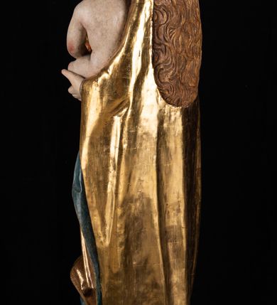 Zdjęcie nr 10: Rzeźba pełnoplastyczna, przyścienna. Przedstawienie Matki Boskiej z Dzieciątkiem ukazanej frontalnie, w całej postaci, w postawie stojącej, z ugiętymi w łokciach rękami; w prawej dłoni trzyma przed sobą berło, prawą obejmuje Dzieciątko. Twarz owalna, o jasnej karnacji, drobnych rysach, z wysokim czołem, okolona włosami spływającymi na ramiona i plecy. Na głowie złota otwarta korona (wtórna). Ubrana w długą suknię z długimi rękawami, zmarszczoną pionowymi równoległymi fałdami, przewiązaną w pasie. Na ramiona nałożony złoty płaszcz z błękitną podszewką, okrywający całą postać i odwijający się pod prawą ręką i przy podstawie okazałymi fałdami muszlowymi. Nagie Dzieciątko o pulchnym ciele siedzi na lewym przedramieniu Matki. Kulista głowa na krótkiej szyi okolona kędzierzawymi włosami. Prawą dłonią błogosławi, w lewej trzyma kulę. 