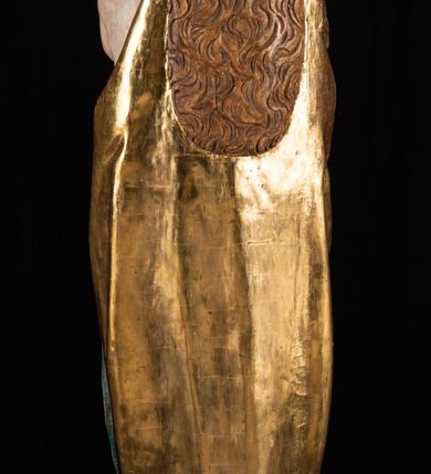 Zdjęcie nr 9: Rzeźba pełnoplastyczna, przyścienna. Przedstawienie Matki Boskiej z Dzieciątkiem ukazanej frontalnie, w całej postaci, w postawie stojącej, z ugiętymi w łokciach rękami; w prawej dłoni trzyma przed sobą berło, prawą obejmuje Dzieciątko. Twarz owalna, o jasnej karnacji, drobnych rysach, z wysokim czołem, okolona włosami spływającymi na ramiona i plecy. Na głowie złota otwarta korona (wtórna). Ubrana w długą suknię z długimi rękawami, zmarszczoną pionowymi równoległymi fałdami, przewiązaną w pasie. Na ramiona nałożony złoty płaszcz z błękitną podszewką, okrywający całą postać i odwijający się pod prawą ręką i przy podstawie okazałymi fałdami muszlowymi. Nagie Dzieciątko o pulchnym ciele siedzi na lewym przedramieniu Matki. Kulista głowa na krótkiej szyi okolona kędzierzawymi włosami. Prawą dłonią błogosławi, w lewej trzyma kulę. 