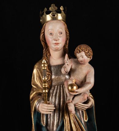 Zdjęcie nr 1: Rzeźba pełnoplastyczna, przyścienna. Przedstawienie Matki Boskiej z Dzieciątkiem ukazanej frontalnie, w całej postaci, w postawie stojącej, z ugiętymi w łokciach rękami; w prawej dłoni trzyma przed sobą berło, prawą obejmuje Dzieciątko. Twarz owalna, o jasnej karnacji, drobnych rysach, z wysokim czołem, okolona włosami spływającymi na ramiona i plecy. Na głowie złota otwarta korona (wtórna). Ubrana w długą suknię z długimi rękawami, zmarszczoną pionowymi równoległymi fałdami, przewiązaną w pasie. Na ramiona nałożony złoty płaszcz z błękitną podszewką, okrywający całą postać i odwijający się pod prawą ręką i przy podstawie okazałymi fałdami muszlowymi. Nagie Dzieciątko o pulchnym ciele siedzi na lewym przedramieniu Matki. Kulista głowa na krótkiej szyi okolona kędzierzawymi włosami. Prawą dłonią błogosławi, w lewej trzyma kulę. 