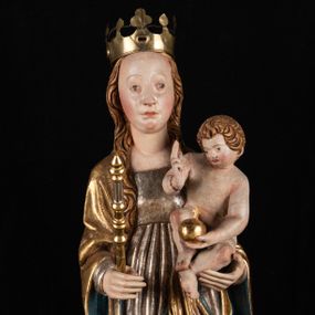 Zdjęcie nr 1: Rzeźba pełnoplastyczna, przyścienna. Przedstawienie Matki Boskiej z Dzieciątkiem ukazanej frontalnie, w całej postaci, w postawie stojącej, z ugiętymi w łokciach rękami; w prawej dłoni trzyma przed sobą berło, prawą obejmuje Dzieciątko. Twarz owalna, o jasnej karnacji, drobnych rysach, z wysokim czołem, okolona włosami spływającymi na ramiona i plecy. Na głowie złota otwarta korona (wtórna). Ubrana w długą suknię z długimi rękawami, zmarszczoną pionowymi równoległymi fałdami, przewiązaną w pasie. Na ramiona nałożony złoty płaszcz z błękitną podszewką, okrywający całą postać i odwijający się pod prawą ręką i przy podstawie okazałymi fałdami muszlowymi. Nagie Dzieciątko o pulchnym ciele siedzi na lewym przedramieniu Matki. Kulista głowa na krótkiej szyi okolona kędzierzawymi włosami. Prawą dłonią błogosławi, w lewej trzyma kulę. 