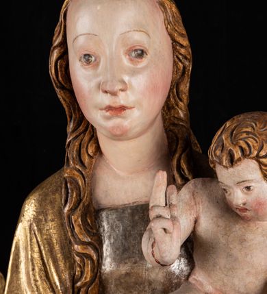 Zdjęcie nr 12: Rzeźba pełnoplastyczna, przyścienna. Przedstawienie Matki Boskiej z Dzieciątkiem ukazanej frontalnie, w całej postaci, w postawie stojącej, z ugiętymi w łokciach rękami; w prawej dłoni trzyma przed sobą berło, prawą obejmuje Dzieciątko. Twarz owalna, o jasnej karnacji, drobnych rysach, z wysokim czołem, okolona włosami spływającymi na ramiona i plecy. Na głowie złota otwarta korona (wtórna). Ubrana w długą suknię z długimi rękawami, zmarszczoną pionowymi równoległymi fałdami, przewiązaną w pasie. Na ramiona nałożony złoty płaszcz z błękitną podszewką, okrywający całą postać i odwijający się pod prawą ręką i przy podstawie okazałymi fałdami muszlowymi. Nagie Dzieciątko o pulchnym ciele siedzi na lewym przedramieniu Matki. Kulista głowa na krótkiej szyi okolona kędzierzawymi włosami. Prawą dłonią błogosławi, w lewej trzyma kulę. 