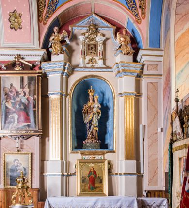 Zdjęcie nr 1: Ołtarz przyścienny, architektoniczny, jednoosiowy, jednokondygnacyjny ze zwieńczeniem. Ołtarz sarkofagowy z murowaną mensą i polichromowanym antepedium z motywem gorejącego serca Marii ujętego parą gałązek laurowych. Część środkową flankuje para zdwojonych lizen osadzonych na wysokich cokołach. Ustawione lekko skośnie na zewnątrz podpory wspierają przerwane i wyłamujące się ponad nimi belkowanie. Pole części środkowej i partii belkowania zajmuje nisza w kształcie stojącego prostokąta zamkniętego półkoliście. Zwieńczenie retabulum ujęte jest parą spływów oraz prostopadłościennych cokołów. Szczyt jest w formie trójkątnego przyczółka. W niszy części środkowej znajduje się figura Madonny z Dzieciątkiem. W zwieńczeniu natomiast jest niewielki obraz Matki Boskiej Częstochowskiej w obramieniu w formie architektonicznej nastawy ołtarzowej ujętej parą osadzonych na wysokich cokołach, ustawionych skośnie na zewnątrz filarów wspierających wyłamujące się ponad nimi przerwane belkowanie. Zwieńczenie ujmuje para ornamentalnych spływów wolutowych. Poniżej obrazu znajduje się relikwiarz ujęty ornamentyką rokokową, natomiast powyżej jest monogram maryjny w bogatej dekoracji ornamentalnej. Pośrodku zwieńczenia jest promienista gloria. Struktura biała, detale w kolorze czerwonym i złocone. W polu przyczółka w szczycie ołtarza jest oko Opatrzności Bożej. Na ujmujących zwieńczenie cokołach znajduje się para figur siedzących aniołów w złoconych szatach. Kolorystyka struktury retabulum utrzymana w kolorze beżowym, detal architektoniczny marmoryzowany w odcieniach błękitu i złocony.