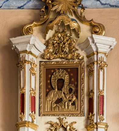 Zdjęcie nr 8: Ołtarz przyścienny, architektoniczny, jednoosiowy, jednokondygnacyjny ze zwieńczeniem. Ołtarz sarkofagowy z murowaną mensą i polichromowanym antepedium z motywem gorejącego serca Marii ujętego parą gałązek laurowych. Część środkową flankuje para zdwojonych lizen osadzonych na wysokich cokołach. Ustawione lekko skośnie na zewnątrz podpory wspierają przerwane i wyłamujące się ponad nimi belkowanie. Pole części środkowej i partii belkowania zajmuje nisza w kształcie stojącego prostokąta zamkniętego półkoliście. Zwieńczenie retabulum ujęte jest parą spływów oraz prostopadłościennych cokołów. Szczyt jest w formie trójkątnego przyczółka. W niszy części środkowej znajduje się figura Madonny z Dzieciątkiem. W zwieńczeniu natomiast jest niewielki obraz Matki Boskiej Częstochowskiej w obramieniu w formie architektonicznej nastawy ołtarzowej ujętej parą osadzonych na wysokich cokołach, ustawionych skośnie na zewnątrz filarów wspierających wyłamujące się ponad nimi przerwane belkowanie. Zwieńczenie ujmuje para ornamentalnych spływów wolutowych. Poniżej obrazu znajduje się relikwiarz ujęty ornamentyką rokokową, natomiast powyżej jest monogram maryjny w bogatej dekoracji ornamentalnej. Pośrodku zwieńczenia jest promienista gloria. Struktura biała, detale w kolorze czerwonym i złocone. W polu przyczółka w szczycie ołtarza jest oko Opatrzności Bożej. Na ujmujących zwieńczenie cokołach znajduje się para figur siedzących aniołów w złoconych szatach. Kolorystyka struktury retabulum utrzymana w kolorze beżowym, detal architektoniczny marmoryzowany w odcieniach błękitu i złocony.