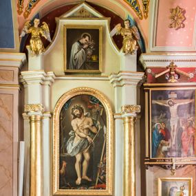 Zdjęcie nr 1: Ołtarz przyścienny, architektoniczny, jednoosiowy, jednokondygnacyjny ze zwieńczeniem. Ołtarz sarkofagowy z murowaną mensą i polichromowanym antepedium z motywem krzyża z koroną cierniową pośrodku. Część środkowa ujęta jest parą półkolumn osadzonych na postumentach  i przylegających do pary pilastrów. Ustawione lekko skośnie na zewnątrz podpory wspierają przerwane i wyłamujący się ponad nimi wysoki fryz oraz gzyms. Pole części środkowej i partii belkowania zajmuje płytka wnęka w kształcie stojącego prostokąta zamkniętego półkoliście. Zwieńczenie retabulum ujęte jest parą spływów oraz prostopadłościennych cokołów. Szczyt jest w formie trójkątnego przyczółka. Obraz w części środkowej ma kształt stojącego prostokąta zamkniętego półkoliście i przedstawia Męża Boleści wśród narzędzi męki Pańskiej. W zwieńczeniu jest obraz w kształcie stojącego prostokąta z wizerunkiem św. Stanisława Kostki. Pole przyczółka wypełnia polichromia przedstawiająca oko Opatrzności Bożej. Na ujmujących zwieńczenie cokołach znajduje się para figur siedzących aniołów w złoconych szatach. Kolorystyka struktury retabulum utrzymana jest w kolorze białym i jasnożółtym, detal architektoniczny jest złocony.         