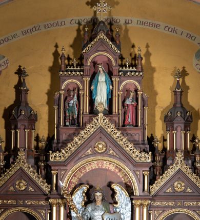 Zdjęcie nr 10: Ołtarz architektoniczny, jednokondygnacyjny, trójosiowy, ze zwieńczeniem. Ołtarz w formie prostopadłościanu z drewnianą mensą i antepedium artykułowanym półkolumienkami, pomiędzy którymi są płytkie wnęki zamknięte półkoliście z płaskorzeźbionymi wizerunkami 4 ewangelistów. Na mensie tabernakulum w formie prostopadłościennej szafki zwieńczone jest tronem wystawienia w kształcie baldachimu wspartego na podwójnych parach kolumienek, zwieńczonego po środku ażurową latarnią z kopułą oraz pinaklami na narożach. Po bokach tabernakulum ujmuje rząd trzech, osadzonych na wysokim cokole niszy z figurami aniołów.  
Retabulum osadzone jest na zdwojonym cokole. Predella artykułowana jest płaskorzeźbionymi płycinami w kształcie zbliżonym do kwadratu, wydzielonymi smukłymi cokołami, na których osadzone są kolumienki ujmujące osie części środkowej retabulum. Każda z osi ma formę prostokątnej niszy zamkniętej łukiem półkolistym. Niszę środkową ujmuje para kolumienek wspierających przerwane w partii architrawu i fryzu belkowanie oraz gzyms wieńczący, przybierający kształt trójkątnego przyczółka, wspierany dodatkowo parą kolumienek w partii fryzu. Nisze boczne ujmują pojedyncze pary kolumienek wspierających przerwany architraw i fryz oraz trójkątny przyczółek. Dodatkowo boki części środkowej retabulum ujmuje para niewielkich, ażurowych uszaków w formie przypór.  Zwieńczenie części środkowej tworzy struktura trójprzelotowego łuku triumfalnego zamkniętego po środku gzymsem w kształcie trójkątnego przyczółka. Zwieńczenia osi bocznych są w formie latarni zamkniętych kopułami. W osi środkowej znajduje się figura św. Michała Archanioła, po lewej św. Wojciecha, po prawej św. Stanisława. W zwieńczeniu, po środku jest rzeźba Matki Boskiej Niepokalanie Poczętej, po lewej św. Floriana, po prawej św. Kazimierza Jagiellończyka. Strukturę retabulum zdobi stylizowana, płaskorzeźbiona i malowana ornamentyka roślinna. Kolorystyka ołtarza utrzymana jest w odcieniach brązów, ornamentyka jest złocona. 

