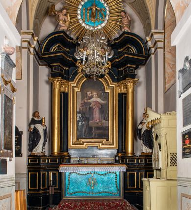 Zdjęcie nr 1: Przyścienna, jednoosiowa i jednokondygnacyjna struktura ołtarza uzyskała kształt nastawy architektonicznej ze zwieńczeniem. Drewniany stipes ołtarzowy przyjął formę leżącego prostopadłościanu podtrzymującego mensę, ustawionego na dwustopniowym podeście. Drewniane antependium ujęto profilowaną ramą z polem udekorowanym monogramem maryjnym w centrum, otoczonym rzeźbionym różańcem przy zewnętrznych krawędziach. Stipes przylega do  trzystrefowego, wysokiego cokołu wspierającego nastawę. Kolejne strefy zostały wydzielone za pomocą poziomych profili. Drugą i trzecią strefę cokołu ozdobiono obramionymi, prostokątnymi płycinami - w drugiej strefie w kształcie stojących prostokątów, a w trzeciej leżących. Kondygnację wsparto na zdwojonych pilastrach o korynckich głowicach, przed którymi ustawiono korynckie kolumny podtrzymujące imposty ze wspartym na nim przerwanym belkowaniem wyłamanym na ich osi. Na belkowaniu widoczne są dwa półkoliste przyczółki z klęczącymi na nich dwoma aniołkami. W kondygnacji pomiędzy pilastrami i kolumnami usytuowano pole obrazowe obramienione profilowaną ramą w kształcie stojącego prostokąta zwieńczonego nadwieszonym łukiem odcinkowym. Rama ujmuje obraz przedstawiający św. Józefa z Dzieciątkiem Jezus. Kondygnację flankują ustawione na cokole retabulum figury św. Dominika i św. Katarzyny ze Sieny. Na osi pola obrazowego w kondygnacji, zawieszono na belkowaniu fantazyjny kartusz z monogramem maryjnym na tle obłoków z uskrzydlonymi główkami anielskimi, powyżej którego w zwieńczeniu retabulum znalazła się promienista gloria z chrystogramem "IHS" otoczonym koliście obłokami. Litery monogramu utworzono z płaskorzeźbionych, złoconych róż w niebieskim polu. W centrum litery "H" na konsolce ukazano w pełnej postaci stojące Dzieciątko Jezusa z rozłożonymi rękami. Struktura ołtarza została pomalowana na czarno, natomiast kolumny, głowice pilastrów, profile architektoniczne oraz glorię i skrzydła aniołków wyzłocono, obłoki w glorii posrebrzono, a pole antependium i glorii pomalowano na niebiesko. Rzeźby świętych dominikańskich, aniołów i Dzieciątka Jezus uzyskały naturalistyczną polichromię.  