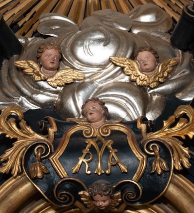 Zdjęcie nr 6: Przyścienna, jednoosiowa i jednokondygnacyjna struktura ołtarza uzyskała kształt nastawy architektonicznej ze zwieńczeniem. Drewniany stipes ołtarzowy przyjął formę leżącego prostopadłościanu podtrzymującego mensę, ustawionego na dwustopniowym podeście. Drewniane antependium ujęto profilowaną ramą z polem udekorowanym monogramem maryjnym w centrum, otoczonym rzeźbionym różańcem przy zewnętrznych krawędziach. Stipes przylega do  trzystrefowego, wysokiego cokołu wspierającego nastawę. Kolejne strefy zostały wydzielone za pomocą poziomych profili. Drugą i trzecią strefę cokołu ozdobiono obramionymi, prostokątnymi płycinami - w drugiej strefie w kształcie stojących prostokątów, a w trzeciej leżących. Kondygnację wsparto na zdwojonych pilastrach o korynckich głowicach, przed którymi ustawiono korynckie kolumny podtrzymujące imposty ze wspartym na nim przerwanym belkowaniem wyłamanym na ich osi. Na belkowaniu widoczne są dwa półkoliste przyczółki z klęczącymi na nich dwoma aniołkami. W kondygnacji pomiędzy pilastrami i kolumnami usytuowano pole obrazowe obramienione profilowaną ramą w kształcie stojącego prostokąta zwieńczonego nadwieszonym łukiem odcinkowym. Rama ujmuje obraz przedstawiający św. Józefa z Dzieciątkiem Jezus. Kondygnację flankują ustawione na cokole retabulum figury św. Dominika i św. Katarzyny ze Sieny. Na osi pola obrazowego w kondygnacji, zawieszono na belkowaniu fantazyjny kartusz z monogramem maryjnym na tle obłoków z uskrzydlonymi główkami anielskimi, powyżej którego w zwieńczeniu retabulum znalazła się promienista gloria z chrystogramem "IHS" otoczonym koliście obłokami. Litery monogramu utworzono z płaskorzeźbionych, złoconych róż w niebieskim polu. W centrum litery "H" na konsolce ukazano w pełnej postaci stojące Dzieciątko Jezusa z rozłożonymi rękami. Struktura ołtarza została pomalowana na czarno, natomiast kolumny, głowice pilastrów, profile architektoniczne oraz glorię i skrzydła aniołków wyzłocono, obłoki w glorii posrebrzono, a pole antependium i glorii pomalowano na niebiesko. Rzeźby świętych dominikańskich, aniołów i Dzieciątka Jezus uzyskały naturalistyczną polichromię.  