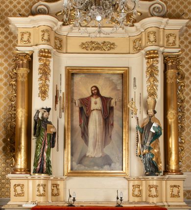 Zdjęcie nr 1: Przyścienny, jednokondygnacyjny ołtarz boczny uzyskał strukturę architektoniczną ze zwieńczeniem. Drewniany stipes ołtarzowy w formie prostopadłościanu, ustawiony na jednostopniowym podeście, podtrzymuję mensę. Jego lico zdobi aplikacja symbolizująca płonące Serce Jezusa w promienistym otoku. Retabulum ustawiono na wysokim dwupoziomowym cokole. Pierwszy poziom tworzy prostopadłościenna struktura dekorowana dwiema płycinami w formie stojącego prostokąta zwieńczona profilowanym gzymsem. Nad drugi poziomie znalazła się przerwana w osi środkowej wklęsło-wypułka strefa cokołowa z płycinami ozdobionymi czworobokami ze stylizowanego ornamentu roślinnego. Wspiera ona flankujące kondygnację dwa pilastry z głowicami wolutowymi o trzonach zdobionych zwisami roślinnymi na wstęgach oraz dwie kolumny z kapitelami kompozytowymi. Podpory podtrzymują belkowanie półkoliście wyłamane na osi pilastrów z rozbudowanym architrawem, powtarzającym układ górnej strefy cokołowej. Po bokach nastawy widoczne są dwa uszaki zredukowane do ażurowej wici roślinnej. Zwieńczenie uzyskało kształt leżącego prostokąta z wklęsłymi bokami przechodzącymi w spływy wolutowe. Wieńczy je gzyms koronujący w kształcie nadwieszonego łuku odcinkowego z podwieszonym ornamentem liściastym. Na gzymsie ustawiono na osi krzyż. W polu kondygnacji umieszczono pole obrazowe w kształcie stojącego prostokąta zamknięte profilowaną ramą z wyobrażeniem Najświętszego Serca Pana Jezusa. Ujmuje go figura św. Jana Kantego i św. Biskupa ustawione na półkoliście wyłamanych fragmentach cokołu. W zwieńczenia umieszczono w owalu obraz św. Tekli. Strukturę polichromowano w kolorze kości słoniowej oraz beżowej, natomiast kolumny, partie ornamentu, profile pozłocono. 