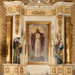 Zdjęcie nr 1: Przyścienny, jednokondygnacyjny ołtarz boczny uzyskał strukturę architektoniczną ze zwieńczeniem. Drewniany stipes ołtarzowy w formie prostopadłościanu, ustawiony na jednostopniowym podeście, podtrzymuję mensę. Jego lico zdobi aplikacja symbolizująca płonące Serce Jezusa w promienistym otoku. Retabulum ustawiono na wysokim dwupoziomowym cokole. Pierwszy poziom tworzy prostopadłościenna struktura dekorowana dwiema płycinami w formie stojącego prostokąta zwieńczona profilowanym gzymsem. Nad drugi poziomie znalazła się przerwana w osi środkowej wklęsło-wypułka strefa cokołowa z płycinami ozdobionymi czworobokami ze stylizowanego ornamentu roślinnego. Wspiera ona flankujące kondygnację dwa pilastry z głowicami wolutowymi o trzonach zdobionych zwisami roślinnymi na wstęgach oraz dwie kolumny z kapitelami kompozytowymi. Podpory podtrzymują belkowanie półkoliście wyłamane na osi pilastrów z rozbudowanym architrawem, powtarzającym układ górnej strefy cokołowej. Po bokach nastawy widoczne są dwa uszaki zredukowane do ażurowej wici roślinnej. Zwieńczenie uzyskało kształt leżącego prostokąta z wklęsłymi bokami przechodzącymi w spływy wolutowe. Wieńczy je gzyms koronujący w kształcie nadwieszonego łuku odcinkowego z podwieszonym ornamentem liściastym. Na gzymsie ustawiono na osi krzyż. W polu kondygnacji umieszczono pole obrazowe w kształcie stojącego prostokąta zamknięte profilowaną ramą z wyobrażeniem Najświętszego Serca Pana Jezusa. Ujmuje go figura św. Jana Kantego i św. Biskupa ustawione na półkoliście wyłamanych fragmentach cokołu. W zwieńczenia umieszczono w owalu obraz św. Tekli. Strukturę polichromowano w kolorze kości słoniowej oraz beżowej, natomiast kolumny, partie ornamentu, profile pozłocono. 