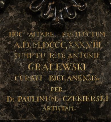 Zdjęcie nr 3: Ołtarz architektoniczny, jednokondygnacyjny ze zwieńczeniem. Mensę ujmują dwa ukośnie ustawione cokoły z wolutami, na których posadowione ukośnie zdwojone pilastry z liściastymi wolutami u podstawy i z liściastymi wolutami w funkcji kapiteli, dźwigających odcinki belkowania. Nad belkowaniem klęczące na wolutach anioły. Zwieńczenie ujęte spływami wolutowymi zakończone fantazyjnymi wolutami z liściem. W centrum ołtarza pole w formie stojącego prostokąta ujęte profilowaną ramą, zwieńczone liściastymi wolutami i rozłożystym kwiatem; w polu obraz z przedstawieniem Matki Boskiej z Dzieciątkiem. W zwieńczeniu pole wpisane w owal, obwiedzione profilowanym obramieniem z wolutami; w polu płaskorzeźba z przedstawieniem św. Józefa z Dzieciątkiem. W dolnej części nastawy inskrypcja: „HOC ALTARE EXSTRUCTUM / A(NNO) D(OMINI) M. DCCC, XXX, VIII. / SUMPTU R(EVERENDI) D(OMINI) ANTONII / GRALEWSKI / CURATI BIELANENSIS. / PER / D(OMINUM) PAULINUM CZEKIERSKI / ARTISTAM”.