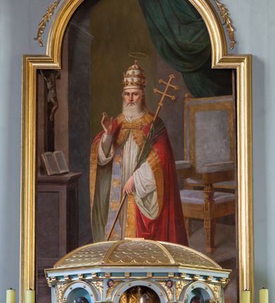 Zdjęcie nr 7: Nastawa ołtarza głównego przyjęła formę przyściennej, trójosiowej, jednokondygnacyjnej struktury architektonicznej ze wieńczeniem. Drewniany stipes ołtarzowy uzyskał kształt leżącego prostopadłościanu podtrzymującego mensę z portatylem, ustawionego na jednostopniowym podeście. Front stipesu udekorowano trzema płycinami obwiedzionymi profilowanymi listwami z rzeźbionymi ornamentami w polach. Na mensie ustawiono drewniane tabernakulum na rzucie trapezu. W dolnej części artykułują je czworoboczne płyciny z ornamentem geometrycznym, rozdzielone spływami wolutowymi podtrzymującymi profilowany gzyms, a w górnej części rozbudowany tron wystawienia. Prostopadłościenne, pancerne tabernakulum usytuowano na osi zdobiąc jego czworoboczne drzwiczki płyciną z trybowanym przedstawieniem kielicha w otoczeniu winnej latorośli i kłosów zbóż. Tron wystawienia przyjął formę trójarkadowej kapliczki zwieńczonej gzymsem koronującym i spłaszczonym dachem pokrytym złoconą rybią łuską. Arkady wsparto na korynckich, kanelowanych kolumienkach. W przyłuczach arkady środkowej, wypełnionej niszą na monstrancję, ukazano uskrzydlone dwie główki anielskie, a w przyłuczach arkad skrajnych motywy ornamentalne. Pod arkadami w osiach skrajnych umieszczono w niszach klęczących na jedno kolana na postumentach adorujących aniołów. Wsparty na arkadach gzyms koronujący ozdobiono profilowaniem i rytmicznie powtarzającymi się konsolkami. Za stipesem ustawiono strukturę ołtarzowa wspartą na wysokim cokole, artykułowaną czterema wysuniętym do przodu dwustopniowymi postumentami dekorowanymi profilowanym gzymsowaniem oraz prostokątnymi płycinami ujętymi w profilowane obramienia. W górnej strefie w płycinach od frontu wyobrażono uskrzydlone głowy symboli czterech Ewangelistów. Idę od lewej jest to głowa woła, anioła, orła i lwa. Natomiast w dolne strefie w płycinach znalazły się od lewej: skrzyżowane bicze z trzciną, na tle których wyobrażono chustę Weroniki, świecznik siedmioramienny z miedzianym wężem na palu na tle pektorału żydowskiego arcykapłana, tablice Dekalogu na tle skrzyżowanych trąb oraz krzyż skrzyżowany z kolumną biczowania wraz z lancą i gąbką na kiju. Pomiędzy postumentami w osiach skrajnych partii cokołowej usytuowano dwoje drzwi prowadzących do zakrystii, zdobionych czworobocznymi płycinami. Na postumentach ustawiono cztery kanelowane kolumny o kapitelach kompozytowych z impostami podtrzymujących belkowanie wyłamane na ich osi. Pomiędzy kolumnami artykułującymi kondygnację w osi środkowej umieszczono pole obrazowe, a w osiach skrajnych półkoliste nisze z ustawionymi w nich na postumentach figurami ŚŚ. Apostołów Piotra i Pawła. Zarówno nad polem obrazowym, jak i nad niszami oraz pod nimi widoczny jest ornament roślinny. Pole obrazowe na osi retabulum przyjęło kształt stojącego prostokąta z nadwieszonym półkolistym łukiem odcinkowym. Ujmuje je profilowana rama. W polu umieszczono obraz Wniebowzięcia Najświętszej Marii Panny, a na dwóch zasuwach przedstawienie św. Urbana oraz św. Barbary. Na belkowaniu w osiach skrajnych nad kolumnami zewnętrznymi usytuowano dwa przerwane przyczółki z leżącymi na nich parą aniołów trzymających krzyż i kotwicę. Natomiast na osi kolumn wewnętrznych na postumentach siedzą dwa złocone putta. Zwieńczenie ołtarza przyjęło kształt leżącego prostokąta flankowanego przez pilaster i kolumienkę podtrzymujących odcinki wyłamanego belkowania, na którym wsparto półkolisty, profilowany łuk odcinkowy wieńczący całość. Ponad tymi podporami umieszczono złocone, siedzące putta, a na osi łuku wieńczącego w promieniach z obłoczkami gołębicę Ducha Świętego. W polu zwieńczenia usytuowano półkolistą niszę ze stojącą figurą Boga Ojca. Ujmuje ją półkoliste obramienie zdobione stylizowaną ornamentyką roślinno-geometryczną. Strukturę architektoniczną retabulum polichromowano w tonacji jasnopastelowej zieleni, ornamenty, profile architektoniczne zostały wyzłocone, natomiast figury apostołów, Boga Ojca oraz aniołów przy tabernakulum i w zwieńczeniu w osiach skrajnych zostały naturalistycznie polichromowane. 