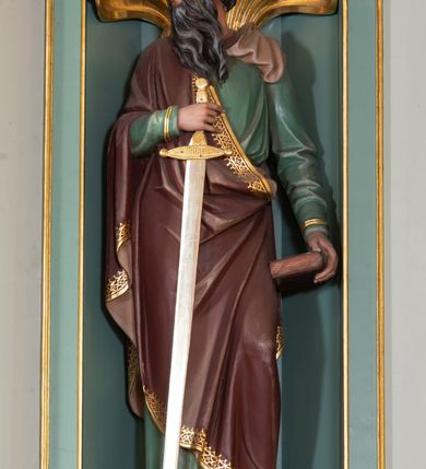 Zdjęcie nr 4: Nastawa ołtarza głównego przyjęła formę przyściennej, trójosiowej, jednokondygnacyjnej struktury architektonicznej ze wieńczeniem. Drewniany stipes ołtarzowy uzyskał kształt leżącego prostopadłościanu podtrzymującego mensę z portatylem, ustawionego na jednostopniowym podeście. Front stipesu udekorowano trzema płycinami obwiedzionymi profilowanymi listwami z rzeźbionymi ornamentami w polach. Na mensie ustawiono drewniane tabernakulum na rzucie trapezu. W dolnej części artykułują je czworoboczne płyciny z ornamentem geometrycznym, rozdzielone spływami wolutowymi podtrzymującymi profilowany gzyms, a w górnej części rozbudowany tron wystawienia. Prostopadłościenne, pancerne tabernakulum usytuowano na osi zdobiąc jego czworoboczne drzwiczki płyciną z trybowanym przedstawieniem kielicha w otoczeniu winnej latorośli i kłosów zbóż. Tron wystawienia przyjął formę trójarkadowej kapliczki zwieńczonej gzymsem koronującym i spłaszczonym dachem pokrytym złoconą rybią łuską. Arkady wsparto na korynckich, kanelowanych kolumienkach. W przyłuczach arkady środkowej, wypełnionej niszą na monstrancję, ukazano uskrzydlone dwie główki anielskie, a w przyłuczach arkad skrajnych motywy ornamentalne. Pod arkadami w osiach skrajnych umieszczono w niszach klęczących na jedno kolana na postumentach adorujących aniołów. Wsparty na arkadach gzyms koronujący ozdobiono profilowaniem i rytmicznie powtarzającymi się konsolkami. Za stipesem ustawiono strukturę ołtarzowa wspartą na wysokim cokole, artykułowaną czterema wysuniętym do przodu dwustopniowymi postumentami dekorowanymi profilowanym gzymsowaniem oraz prostokątnymi płycinami ujętymi w profilowane obramienia. W górnej strefie w płycinach od frontu wyobrażono uskrzydlone głowy symboli czterech Ewangelistów. Idę od lewej jest to głowa woła, anioła, orła i lwa. Natomiast w dolne strefie w płycinach znalazły się od lewej: skrzyżowane bicze z trzciną, na tle których wyobrażono chustę Weroniki, świecznik siedmioramienny z miedzianym wężem na palu na tle pektorału żydowskiego arcykapłana, tablice Dekalogu na tle skrzyżowanych trąb oraz krzyż skrzyżowany z kolumną biczowania wraz z lancą i gąbką na kiju. Pomiędzy postumentami w osiach skrajnych partii cokołowej usytuowano dwoje drzwi prowadzących do zakrystii, zdobionych czworobocznymi płycinami. Na postumentach ustawiono cztery kanelowane kolumny o kapitelach kompozytowych z impostami podtrzymujących belkowanie wyłamane na ich osi. Pomiędzy kolumnami artykułującymi kondygnację w osi środkowej umieszczono pole obrazowe, a w osiach skrajnych półkoliste nisze z ustawionymi w nich na postumentach figurami ŚŚ. Apostołów Piotra i Pawła. Zarówno nad polem obrazowym, jak i nad niszami oraz pod nimi widoczny jest ornament roślinny. Pole obrazowe na osi retabulum przyjęło kształt stojącego prostokąta z nadwieszonym półkolistym łukiem odcinkowym. Ujmuje je profilowana rama. W polu umieszczono obraz Wniebowzięcia Najświętszej Marii Panny, a na dwóch zasuwach przedstawienie św. Urbana oraz św. Barbary. Na belkowaniu w osiach skrajnych nad kolumnami zewnętrznymi usytuowano dwa przerwane przyczółki z leżącymi na nich parą aniołów trzymających krzyż i kotwicę. Natomiast na osi kolumn wewnętrznych na postumentach siedzą dwa złocone putta. Zwieńczenie ołtarza przyjęło kształt leżącego prostokąta flankowanego przez pilaster i kolumienkę podtrzymujących odcinki wyłamanego belkowania, na którym wsparto półkolisty, profilowany łuk odcinkowy wieńczący całość. Ponad tymi podporami umieszczono złocone, siedzące putta, a na osi łuku wieńczącego w promieniach z obłoczkami gołębicę Ducha Świętego. W polu zwieńczenia usytuowano półkolistą niszę ze stojącą figurą Boga Ojca. Ujmuje ją półkoliste obramienie zdobione stylizowaną ornamentyką roślinno-geometryczną. Strukturę architektoniczną retabulum polichromowano w tonacji jasnopastelowej zieleni, ornamenty, profile architektoniczne zostały wyzłocone, natomiast figury apostołów, Boga Ojca oraz aniołów przy tabernakulum i w zwieńczeniu w osiach skrajnych zostały naturalistycznie polichromowane. 