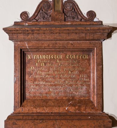 Zdjęcie nr 1: Epitafium w formie kamiennej tablicy w kształcie leżącego prostokąta, ujętej profilowanym obramieniem zwieńczonym krzyżem z parą wolut u podstawy, zdobionych motywem rozetek i liści akantu. Tablicę epitafijną pokrywa złocona inskrypcja „X(IĄDZ) FRANCISZEK SZOTTEK / Proboszcz Kanonik tyt(ularny): / V(ice) Dziekan Oświęcimski - / Dyrektor szkoły panieńskiej - / Obywatel honor(owy): Kęcki / umarł dnia 8. Listopada. 1876. / w roku życia swego - 68 lat. / będąc 5. lat Wikarym ½ roku Administratorem / i 36. lat Proboszczem przy tutejszym / Kościele i Kaplicy J(ana) Kantego. - / Prosi za duszę swoję o Ojcze Nasz i Zdrowaś Marya. –"
