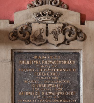 Zdjęcie nr 1: Płyta z czarnego marmuru w formie stojącego prostokąta, ujęta grubą ramą z piaskowca z czterema uszakami, zakończona szczytem z anthemionem. W partii szczytu tarcze z godłami herbów Pelikan i Trąby, zwieńczone otwartą koroną, ujęte skręconym akantem. W polu tablicy złocona inskrypcja: „PAMIĘCI / AUGUSTYNA ROZWADOWSKIEGO / + 1. MARCA 1813. / TERESY z ROZWADOWSKICH / FERENCOWEJ / + 1. MARCA 1816. / MARYI z OPOLSKICH / ROZWADOWSKIEJ / + 28. CZERWCA 1829. / ANTONIEGO ROZWADOWSKIEGO / + 12. LUTEGO 1837. / ROZALII z ROZWADOWSKICH / FOLTAŃSKIEJ / + 5. SIERP(NIA) 1847. / FRANCISZKA FOLTAŃSKIEGO / POCHOWANEGO W KRZĘCINIE, + 2. LUTEGO 1849. / STEFANII FOLTAŃSKIEJ / + 26. LUTEGO 1854. / SPOKÓJ ICH DUSZOM. / Pomnik ten poświęca ANTONINA / z FOLTAŃSKICH DZIĘGIELOWSKA / 1877”.

