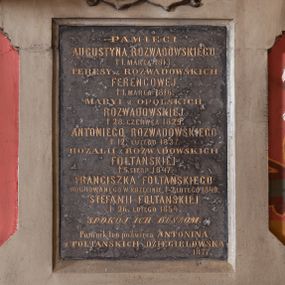 Zdjęcie nr 1: Płyta z czarnego marmuru w formie stojącego prostokąta, ujęta grubą ramą z piaskowca z czterema uszakami, zakończona szczytem z anthemionem. W partii szczytu tarcze z godłami herbów Pelikan i Trąby, zwieńczone otwartą koroną, ujęte skręconym akantem. W polu tablicy złocona inskrypcja: „PAMIĘCI / AUGUSTYNA ROZWADOWSKIEGO / + 1. MARCA 1813. / TERESY z ROZWADOWSKICH / FERENCOWEJ / + 1. MARCA 1816. / MARYI z OPOLSKICH / ROZWADOWSKIEJ / + 28. CZERWCA 1829. / ANTONIEGO ROZWADOWSKIEGO / + 12. LUTEGO 1837. / ROZALII z ROZWADOWSKICH / FOLTAŃSKIEJ / + 5. SIERP(NIA) 1847. / FRANCISZKA FOLTAŃSKIEGO / POCHOWANEGO W KRZĘCINIE, + 2. LUTEGO 1849. / STEFANII FOLTAŃSKIEJ / + 26. LUTEGO 1854. / SPOKÓJ ICH DUSZOM. / Pomnik ten poświęca ANTONINA / z FOLTAŃSKICH DZIĘGIELOWSKA / 1877”.


