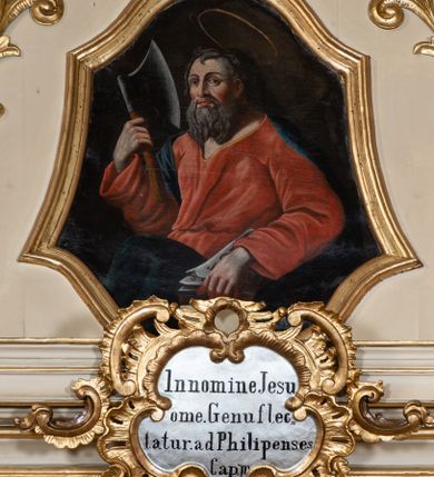 Zdjęcie nr 1: Obraz w formie zbliżonej do trapezu zamkniętego z dwóch stron łukiem falistym. W centrum święty ukazany w półpostaci, zwrócony w trzech czwartych w prawo. W prawej uniesionej ręce trzyma topór, w lewej opuszczonej w dół trzyma księgę. Twarz ma kwadratową, o dużych, migdałowatych oczach, nosie i pełnych ustach; okoloną długą, siwą brodą oraz krótkimi, siwymi włosami. Nad głową ma aureolę. Ubrany jest w luźną, czerwoną suknię, przepasaną w talii oraz ciemnoniebieski płaszcz zarzucony na plecy i prawe ramię, opadający z przodu postaci. Święty ukazany na ciemnobrązowym tle. 