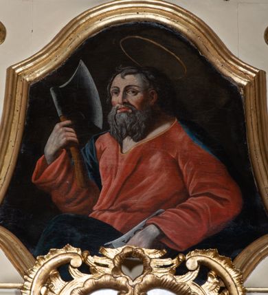 Zdjęcie nr 2: Obraz w formie zbliżonej do trapezu zamkniętego z dwóch stron łukiem falistym. W centrum święty ukazany w półpostaci, zwrócony w trzech czwartych w prawo. W prawej uniesionej ręce trzyma topór, w lewej opuszczonej w dół trzyma księgę. Twarz ma kwadratową, o dużych, migdałowatych oczach, nosie i pełnych ustach; okoloną długą, siwą brodą oraz krótkimi, siwymi włosami. Nad głową ma aureolę. Ubrany jest w luźną, czerwoną suknię, przepasaną w talii oraz ciemnoniebieski płaszcz zarzucony na plecy i prawe ramię, opadający z przodu postaci. Święty ukazany na ciemnobrązowym tle. 
