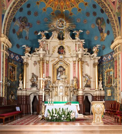 Zdjęcie nr 2: Nastawa ołtarzowa architektoniczna, dwukondygnacyjna, ze zwieńczeniem, pierwsza kondygnacja trójosiowa, druga jednoosiowa, ustawiona na dwustrefowym cokole z wyodrębnionymi, cylindrycznymi fragmentami, z bramkami na osiach bocznych. Ołtarz prostopadłościenny, murowany, z kamienną mensą i kamiennym portatylem. 
Pierwsza kondygnacja wydzielona czterema parami wklęsłych pilastrów o trzonach dekorowanych rocaille'em i zwisami kwiatowymi oraz stojącymi na ich tle dwiema parami kolumn o kapitelach kompozytowych. Podpory dźwigają niepełne belkowanie, przerwane nad polami kondygnacji, obniżone nad zewnętrzną parą kolumn. Na skrajnej partii cokołu nastawy karbowane woluty z fantazyjnymi gruszkowatymi cokołami podtrzymującymi rocaille'owe wazony. W polu środkowym głęboka wnęka w formie stojącego prostokąta zamkniętego łukiem odcinkowym podwójnie nadwieszonym z uskokiem, ujęta profilowaną ramą, z obrazem Ecce Homo w osobnej, podwójnej ramie. Nad nią kartusz rokokowy z napisem „In nomine Jesu / om(n)e Genu flec / tatur. ad Philipenses / Cap(ut) II”. Wnękę flankują figury Matki Boskiej i św. Marii Magdaleny ustawione na rocaille'owych konsolach. Na osiach bocznych figura Dawida i grupa ofiary Izaaka na cokołach z nadlatującymi puttami nad nimi. Druga kondygnacja flankowana trzema parami pilastrów o trzonach przechodzących w spływy wolutowe i osobne woluty, opadające na belkowanie pierwszej kondygnacji, na których siedzą putta i anioły trzymające kartusze z napisami: „ET / GLORIA” i „SOLI / DEO / HONOR”. Kondygnacja zamknięta profilowanym gzymsem wyłamanym na ich osi oraz załamanym w dół nad polem. Na gzymsie fragmenty przerwanego, falistego przyczółka, na których siedzą anioły. W polu obraz św. Macieja w formie zbliżonej do trapezu o dwóch wypukłych bokach, ujęty profilowaną ramą. Pole flankowane akantem, powyżej rocaille'owy kartusz z napisem: „IN / CRUCE / SALUS”. Zwieńczenie w formie zbliżonej do trapezu, o wklęsłych bokach, ujętych wolutami, zamknięte cęgowymi wolutami. W polu obraz Ukrzyżowania w formie zbliżonej do trapezu o dwóch wypukłych bokach, ujęty profilowaną ramą, flankowany akantem. Całość zamknięta płaskorzeźbionym przedstawieniem popiersia Boga Ojca oraz gołębicy Ducha Świętego w glorii, w otoku z obłoków i uskrzydlonych główek anielskich, w glorii promienistej, u dołu szarfa z napisem: „Hic est Filius meus dilectus in quo mihi bene complacui ipsum audite. Luc[a] XVII”. Struktura polichromowana w kolorze beżowym, dolna strefa cokołu brązowa, część trzonów pilastrów pomalowana na kolor jasnoróżowy; trzony kolumn, profile i ornamentyka złocone, detal srebrzony.  


