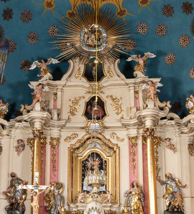 Zdjęcie nr 35: Nastawa ołtarzowa architektoniczna, dwukondygnacyjna, ze zwieńczeniem, pierwsza kondygnacja trójosiowa, druga jednoosiowa, ustawiona na dwustrefowym cokole z wyodrębnionymi, cylindrycznymi fragmentami, z bramkami na osiach bocznych. Ołtarz prostopadłościenny, murowany, z kamienną mensą i kamiennym portatylem. 
Pierwsza kondygnacja wydzielona czterema parami wklęsłych pilastrów o trzonach dekorowanych rocaille'em i zwisami kwiatowymi oraz stojącymi na ich tle dwiema parami kolumn o kapitelach kompozytowych. Podpory dźwigają niepełne belkowanie, przerwane nad polami kondygnacji, obniżone nad zewnętrzną parą kolumn. Na skrajnej partii cokołu nastawy karbowane woluty z fantazyjnymi gruszkowatymi cokołami podtrzymującymi rocaille'owe wazony. W polu środkowym głęboka wnęka w formie stojącego prostokąta zamkniętego łukiem odcinkowym podwójnie nadwieszonym z uskokiem, ujęta profilowaną ramą, z obrazem Ecce Homo w osobnej, podwójnej ramie. Nad nią kartusz rokokowy z napisem „In nomine Jesu / om(n)e Genu flec / tatur. ad Philipenses / Cap(ut) II”. Wnękę flankują figury Matki Boskiej i św. Marii Magdaleny ustawione na rocaille'owych konsolach. Na osiach bocznych figura Dawida i grupa ofiary Izaaka na cokołach z nadlatującymi puttami nad nimi. Druga kondygnacja flankowana trzema parami pilastrów o trzonach przechodzących w spływy wolutowe i osobne woluty, opadające na belkowanie pierwszej kondygnacji, na których siedzą putta i anioły trzymające kartusze z napisami: „ET / GLORIA” i „SOLI / DEO / HONOR”. Kondygnacja zamknięta profilowanym gzymsem wyłamanym na ich osi oraz załamanym w dół nad polem. Na gzymsie fragmenty przerwanego, falistego przyczółka, na których siedzą anioły. W polu obraz św. Macieja w formie zbliżonej do trapezu o dwóch wypukłych bokach, ujęty profilowaną ramą. Pole flankowane akantem, powyżej rocaille'owy kartusz z napisem: „IN / CRUCE / SALUS”. Zwieńczenie w formie zbliżonej do trapezu, o wklęsłych bokach, ujętych wolutami, zamknięte cęgowymi wolutami. W polu obraz Ukrzyżowania w formie zbliżonej do trapezu o dwóch wypukłych bokach, ujęty profilowaną ramą, flankowany akantem. Całość zamknięta płaskorzeźbionym przedstawieniem popiersia Boga Ojca oraz gołębicy Ducha Świętego w glorii, w otoku z obłoków i uskrzydlonych główek anielskich, w glorii promienistej, u dołu szarfa z napisem: „Hic est Filius meus dilectus in quo mihi bene complacui ipsum audite. Luc[a] XVII”. Struktura polichromowana w kolorze beżowym, dolna strefa cokołu brązowa, część trzonów pilastrów pomalowana na kolor jasnoróżowy; trzony kolumn, profile i ornamentyka złocone, detal srebrzony.  


