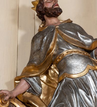 Zdjęcie nr 32: Nastawa ołtarzowa architektoniczna, dwukondygnacyjna, ze zwieńczeniem, pierwsza kondygnacja trójosiowa, druga jednoosiowa, ustawiona na dwustrefowym cokole z wyodrębnionymi, cylindrycznymi fragmentami, z bramkami na osiach bocznych. Ołtarz prostopadłościenny, murowany, z kamienną mensą i kamiennym portatylem. 
Pierwsza kondygnacja wydzielona czterema parami wklęsłych pilastrów o trzonach dekorowanych rocaille'em i zwisami kwiatowymi oraz stojącymi na ich tle dwiema parami kolumn o kapitelach kompozytowych. Podpory dźwigają niepełne belkowanie, przerwane nad polami kondygnacji, obniżone nad zewnętrzną parą kolumn. Na skrajnej partii cokołu nastawy karbowane woluty z fantazyjnymi gruszkowatymi cokołami podtrzymującymi rocaille'owe wazony. W polu środkowym głęboka wnęka w formie stojącego prostokąta zamkniętego łukiem odcinkowym podwójnie nadwieszonym z uskokiem, ujęta profilowaną ramą, z obrazem Ecce Homo w osobnej, podwójnej ramie. Nad nią kartusz rokokowy z napisem „In nomine Jesu / om(n)e Genu flec / tatur. ad Philipenses / Cap(ut) II”. Wnękę flankują figury Matki Boskiej i św. Marii Magdaleny ustawione na rocaille'owych konsolach. Na osiach bocznych figura Dawida i grupa ofiary Izaaka na cokołach z nadlatującymi puttami nad nimi. Druga kondygnacja flankowana trzema parami pilastrów o trzonach przechodzących w spływy wolutowe i osobne woluty, opadające na belkowanie pierwszej kondygnacji, na których siedzą putta i anioły trzymające kartusze z napisami: „ET / GLORIA” i „SOLI / DEO / HONOR”. Kondygnacja zamknięta profilowanym gzymsem wyłamanym na ich osi oraz załamanym w dół nad polem. Na gzymsie fragmenty przerwanego, falistego przyczółka, na których siedzą anioły. W polu obraz św. Macieja w formie zbliżonej do trapezu o dwóch wypukłych bokach, ujęty profilowaną ramą. Pole flankowane akantem, powyżej rocaille'owy kartusz z napisem: „IN / CRUCE / SALUS”. Zwieńczenie w formie zbliżonej do trapezu, o wklęsłych bokach, ujętych wolutami, zamknięte cęgowymi wolutami. W polu obraz Ukrzyżowania w formie zbliżonej do trapezu o dwóch wypukłych bokach, ujęty profilowaną ramą, flankowany akantem. Całość zamknięta płaskorzeźbionym przedstawieniem popiersia Boga Ojca oraz gołębicy Ducha Świętego w glorii, w otoku z obłoków i uskrzydlonych główek anielskich, w glorii promienistej, u dołu szarfa z napisem: „Hic est Filius meus dilectus in quo mihi bene complacui ipsum audite. Luc[a] XVII”. Struktura polichromowana w kolorze beżowym, dolna strefa cokołu brązowa, część trzonów pilastrów pomalowana na kolor jasnoróżowy; trzony kolumn, profile i ornamentyka złocone, detal srebrzony.  


