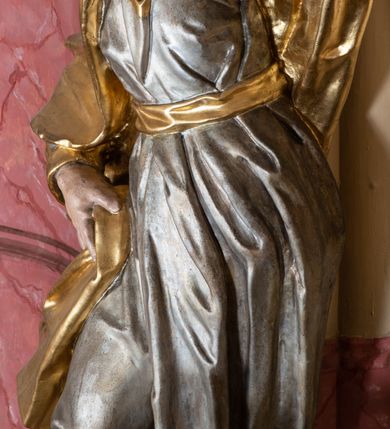 Zdjęcie nr 29: Nastawa ołtarzowa architektoniczna, dwukondygnacyjna, ze zwieńczeniem, pierwsza kondygnacja trójosiowa, druga jednoosiowa, ustawiona na dwustrefowym cokole z wyodrębnionymi, cylindrycznymi fragmentami, z bramkami na osiach bocznych. Ołtarz prostopadłościenny, murowany, z kamienną mensą i kamiennym portatylem. 
Pierwsza kondygnacja wydzielona czterema parami wklęsłych pilastrów o trzonach dekorowanych rocaille&#039;em i zwisami kwiatowymi oraz stojącymi na ich tle dwiema parami kolumn o kapitelach kompozytowych. Podpory dźwigają niepełne belkowanie, przerwane nad polami kondygnacji, obniżone nad zewnętrzną parą kolumn. Na skrajnej partii cokołu nastawy karbowane woluty z fantazyjnymi gruszkowatymi cokołami podtrzymującymi rocaille&#039;owe wazony. W polu środkowym głęboka wnęka w formie stojącego prostokąta zamkniętego łukiem odcinkowym podwójnie nadwieszonym z uskokiem, ujęta profilowaną ramą, z obrazem Ecce Homo w osobnej, podwójnej ramie. Nad nią kartusz rokokowy z napisem „In nomine Jesu / om(n)e Genu flec / tatur. ad Philipenses / Cap(ut) II”. Wnękę flankują figury Matki Boskiej i św. Marii Magdaleny ustawione na rocaille&#039;owych konsolach. Na osiach bocznych figura Dawida i grupa ofiary Izaaka na cokołach z nadlatującymi puttami nad nimi. Druga kondygnacja flankowana trzema parami pilastrów o trzonach przechodzących w spływy wolutowe i osobne woluty, opadające na belkowanie pierwszej kondygnacji, na których siedzą putta i anioły trzymające kartusze z napisami: „ET / GLORIA” i „SOLI / DEO / HONOR”. Kondygnacja zamknięta profilowanym gzymsem wyłamanym na ich osi oraz załamanym w dół nad polem. Na gzymsie fragmenty przerwanego, falistego przyczółka, na których siedzą anioły. W polu obraz św. Macieja w formie zbliżonej do trapezu o dwóch wypukłych bokach, ujęty profilowaną ramą. Pole flankowane akantem, powyżej rocaille&#039;owy kartusz z napisem: „IN / CRUCE / SALUS”. Zwieńczenie w formie zbliżonej do trapezu, o wklęsłych bokach, ujętych wolutami, zamknięte cęgowymi wolutami. W polu obraz Ukrzyżowania w formie zbliżonej do trapezu o dwóch wypukłych bokach, ujęty profilowaną ramą, flankowany akantem. Całość zamknięta płaskorzeźbionym przedstawieniem popiersia Boga Ojca oraz gołębicy Ducha Świętego w glorii, w otoku z obłoków i uskrzydlonych główek anielskich, w glorii promienistej, u dołu szarfa z napisem: „Hic est Filius meus dilectus in quo mihi bene complacui ipsum audite. Luc[a] XVII”. Struktura polichromowana w kolorze beżowym, dolna strefa cokołu brązowa, część trzonów pilastrów pomalowana na kolor jasnoróżowy; trzony kolumn, profile i ornamentyka złocone, detal srebrzony.  


