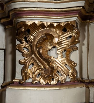 Zdjęcie nr 80: Nastawa ołtarzowa architektoniczna, dwukondygnacyjna, ze zwieńczeniem, pierwsza kondygnacja trójosiowa, druga jednoosiowa, ustawiona na dwustrefowym cokole z wyodrębnionymi, cylindrycznymi fragmentami, z bramkami na osiach bocznych. Ołtarz prostopadłościenny, murowany, z kamienną mensą i kamiennym portatylem. 
Pierwsza kondygnacja wydzielona czterema parami wklęsłych pilastrów o trzonach dekorowanych rocaille'em i zwisami kwiatowymi oraz stojącymi na ich tle dwiema parami kolumn o kapitelach kompozytowych. Podpory dźwigają niepełne belkowanie, przerwane nad polami kondygnacji, obniżone nad zewnętrzną parą kolumn. Na skrajnej partii cokołu nastawy karbowane woluty z fantazyjnymi gruszkowatymi cokołami podtrzymującymi rocaille'owe wazony. W polu środkowym głęboka wnęka w formie stojącego prostokąta zamkniętego łukiem odcinkowym podwójnie nadwieszonym z uskokiem, ujęta profilowaną ramą, z obrazem Ecce Homo w osobnej, podwójnej ramie. Nad nią kartusz rokokowy z napisem „In nomine Jesu / om(n)e Genu flec / tatur. ad Philipenses / Cap(ut) II”. Wnękę flankują figury Matki Boskiej i św. Marii Magdaleny ustawione na rocaille'owych konsolach. Na osiach bocznych figura Dawida i grupa ofiary Izaaka na cokołach z nadlatującymi puttami nad nimi. Druga kondygnacja flankowana trzema parami pilastrów o trzonach przechodzących w spływy wolutowe i osobne woluty, opadające na belkowanie pierwszej kondygnacji, na których siedzą putta i anioły trzymające kartusze z napisami: „ET / GLORIA” i „SOLI / DEO / HONOR”. Kondygnacja zamknięta profilowanym gzymsem wyłamanym na ich osi oraz załamanym w dół nad polem. Na gzymsie fragmenty przerwanego, falistego przyczółka, na których siedzą anioły. W polu obraz św. Macieja w formie zbliżonej do trapezu o dwóch wypukłych bokach, ujęty profilowaną ramą. Pole flankowane akantem, powyżej rocaille'owy kartusz z napisem: „IN / CRUCE / SALUS”. Zwieńczenie w formie zbliżonej do trapezu, o wklęsłych bokach, ujętych wolutami, zamknięte cęgowymi wolutami. W polu obraz Ukrzyżowania w formie zbliżonej do trapezu o dwóch wypukłych bokach, ujęty profilowaną ramą, flankowany akantem. Całość zamknięta płaskorzeźbionym przedstawieniem popiersia Boga Ojca oraz gołębicy Ducha Świętego w glorii, w otoku z obłoków i uskrzydlonych główek anielskich, w glorii promienistej, u dołu szarfa z napisem: „Hic est Filius meus dilectus in quo mihi bene complacui ipsum audite. Luc[a] XVII”. Struktura polichromowana w kolorze beżowym, dolna strefa cokołu brązowa, część trzonów pilastrów pomalowana na kolor jasnoróżowy; trzony kolumn, profile i ornamentyka złocone, detal srebrzony.  


