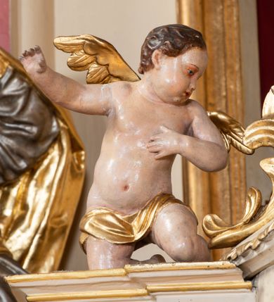Zdjęcie nr 5: Tabernakulum w formie drewnianej, prostopadłościennej skrzynki, obitej blachą, z wypukłym frontem. Drzwiczki w kształcie stojącego prostokąta, w ramie, dekorowane przedstawieniem kielicha z hostią w glorii, ornamentem roślinnym i uskrzydloną główką anielską. Tron wystawienia ustawiony na dwustrefowym cokole, w którego partii zamontowane jest tabernakulum. Przyjmuje formę drewnianej, prostopadłościennej skrzynki z obrotową niszą, flankowaną dwiema parami kolumienek o kanelowanych trzonach, podtrzymujących fragmenty belkowania, nad niszą przyjmującego kształt falistego gzymsu, na którym znajduje się cokół dekorowany ornamentem roślinnym, z leżącym na księdze barankiem, flankowany dwoma aniołkami, Otwór niszy w formie stojącego prostokąta zamkniętego łukiem półkolistym zdobionym lambrekinem. Przed kolumienkami dwie figurki aniołów trzymających świeczniki.



