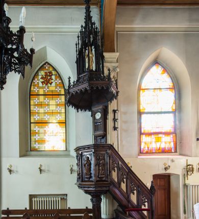 Zdjęcie nr 1: Ambona nadwieszona, umieszczona jest na filarze, z wejściem od prawej strony w postaci jednobiegowych schodów z balustradą w formie wydzielonych kolumienkami, ażurowych płycin zdobionych w narożu ornamentyką roślinną. Wsparty na ośmiobocznym filarze kosz jest na rzucie ośmioboku. Wydzielone kolumienkami ścianki wypełniają prostokątne płyciny zamknięte łukiem w kształcie rybiego pęcherza, z rzeźbionymi  figurami czterech ewangelistów stojących na niewielkich konsolkach. Profilowany parapet ambony zdobi motyw rozetek. Na zaplecku ambony zawieszony jest zegar w drewnianej obudowie. Baldachim na rzucie ośmioboku o krawędziach ujętych fryzem arkadkowym oraz niewielkimi sterczynkami. Zwieńczenie w formie ażurowego pinakla z figurą Jezusa wewnątrz.

Struktura ambony pokryta jest ciemnobrązową bejcą, zaś figura utrzymana w odcieniu naturalnego drewna.
