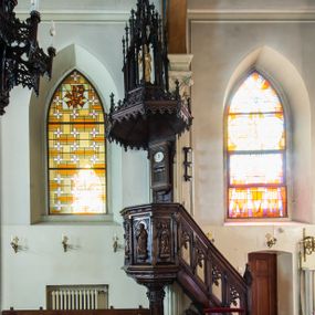 Zdjęcie nr 1: Ambona nadwieszona, umieszczona jest na filarze, z wejściem od prawej strony w postaci jednobiegowych schodów z balustradą w formie wydzielonych kolumienkami, ażurowych płycin zdobionych w narożu ornamentyką roślinną. Wsparty na ośmiobocznym filarze kosz jest na rzucie ośmioboku. Wydzielone kolumienkami ścianki wypełniają prostokątne płyciny zamknięte łukiem w kształcie rybiego pęcherza, z rzeźbionymi  figurami czterech ewangelistów stojących na niewielkich konsolkach. Profilowany parapet ambony zdobi motyw rozetek. Na zaplecku ambony zawieszony jest zegar w drewnianej obudowie. Baldachim na rzucie ośmioboku o krawędziach ujętych fryzem arkadkowym oraz niewielkimi sterczynkami. Zwieńczenie w formie ażurowego pinakla z figurą Jezusa wewnątrz.

Struktura ambony pokryta jest ciemnobrązową bejcą, zaś figura utrzymana w odcieniu naturalnego drewna.
