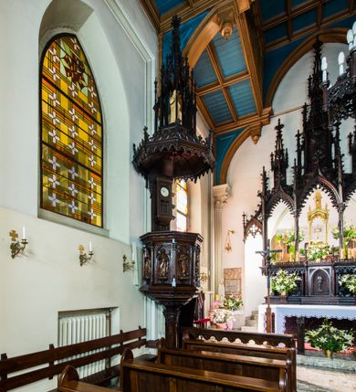 Zdjęcie nr 2: Ambona nadwieszona, umieszczona jest na filarze, z wejściem od prawej strony w postaci jednobiegowych schodów z balustradą w formie wydzielonych kolumienkami, ażurowych płycin zdobionych w narożu ornamentyką roślinną. Wsparty na ośmiobocznym filarze kosz jest na rzucie ośmioboku. Wydzielone kolumienkami ścianki wypełniają prostokątne płyciny zamknięte łukiem w kształcie rybiego pęcherza, z rzeźbionymi  figurami czterech ewangelistów stojących na niewielkich konsolkach. Profilowany parapet ambony zdobi motyw rozetek. Na zaplecku ambony zawieszony jest zegar w drewnianej obudowie. Baldachim na rzucie ośmioboku o krawędziach ujętych fryzem arkadkowym oraz niewielkimi sterczynkami. Zwieńczenie w formie ażurowego pinakla z figurą Jezusa wewnątrz.

Struktura ambony pokryta jest ciemnobrązową bejcą, zaś figura utrzymana w odcieniu naturalnego drewna.
