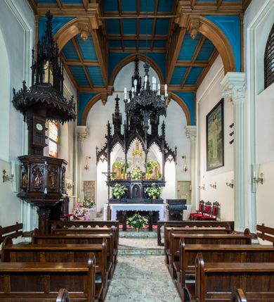 Zdjęcie nr 5: Ambona nadwieszona, umieszczona jest na filarze, z wejściem od prawej strony w postaci jednobiegowych schodów z balustradą w formie wydzielonych kolumienkami, ażurowych płycin zdobionych w narożu ornamentyką roślinną. Wsparty na ośmiobocznym filarze kosz jest na rzucie ośmioboku. Wydzielone kolumienkami ścianki wypełniają prostokątne płyciny zamknięte łukiem w kształcie rybiego pęcherza, z rzeźbionymi  figurami czterech ewangelistów stojących na niewielkich konsolkach. Profilowany parapet ambony zdobi motyw rozetek. Na zaplecku ambony zawieszony jest zegar w drewnianej obudowie. Baldachim na rzucie ośmioboku o krawędziach ujętych fryzem arkadkowym oraz niewielkimi sterczynkami. Zwieńczenie w formie ażurowego pinakla z figurą Jezusa wewnątrz.

Struktura ambony pokryta jest ciemnobrązową bejcą, zaś figura utrzymana w odcieniu naturalnego drewna.
