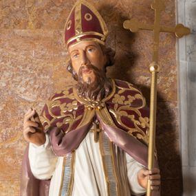 Zdjęcie nr 1: Rzeźba drążona z tyłu stoi na prostokątnej podstawie ustawionej na profilowanej, zwężającej się ku dołowi konsoli przyściennej. Postać biskupa jest ujęta frontalni w nieznacznym kontrapoście z głową lekko skierowaną w prawo. Prawą rękę Marcin ma uniesioną przed siebie na wysokość piersi w lewej zaś trzyma laskę krzyżową. Święty ma pociągłą, wychudzoną twarz o szeroko otwartych oczach, mięsistym nosie i pełnych ustach. Głowę okala broda i lekko kręcone sięgające ramion włosy. Marcin na głowie ma szkarłatną mitrę zdobiną złotą ornamentyką. Ubrany jest w sutannę, białą komże dekorowaną u spodu szeroką koronką, stułę oraz szkarłatną kapę pokrytą złocistym ornamentem i lamowaną złotą tasiemką. Na postumencie widoczny jest podpis: "Ś[WIĘTY] MARCIN".