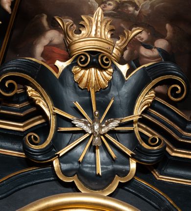 Zdjęcie nr 16: Ołtarz boczny przyjął formę przyściennej, jednokondygnacyjnej i jednoosiowej struktury architektonicznej ze zwieńczeniem. Drewniany stipes ołtarzowy w formie sarkofagu na cokole ustawiono na trójstopniowym podeście. Całą nastawę ustawiono na wysokim, dwustrefowym postumencie, na którym wsparto niski cokół, podtrzymujący zwielokrotnione pilastry o gładkich trzonach i głowicach korynckich oraz flankujący kondygnację dwie pary kolumn. Podpory wspierają wklęsło-wypuklę belkowanie wyłamane na osi kolumn, z umieszczonym na nim na osi pola obrazowego fantazyjnym kartuszem z przedstawieniem gołębicy jako Ducha Świętego. Na belkowaniu, na osi kolumn skrajnych, usytuowano rzeźby stojących aniołów, a na osi kolumn środkowych elementy półkolistego, przerwanego przyczółku z siedzącymi dwoma aniołkami. Zwieńczenie uzyskało kształt leżącego prostokąta o wklęsłych bokach, przechodzących w spływy wolutowe z pilastrami flankującymi pole obrazowe, podtrzymujące wyłamany na osi pilastrów i nadwieszone nad polem obrazowym profilowany gzyms koronujący. Na osi pilastrów ustawiono na nim dwa przyczółki faliste, a na osi retabulum promienistą glorię z chrystogramem "IHS" otoczonym obłokami. Pole obrazowe w kondygnacji uzyskało kształt stojącego prostokąta ujętego profilowaną ramą o nieznacznie wklęsłych bokach i podstawie, zwieńczonego łukiem nadwieszonym z uskokiem. W nim na złoconym tle zawieszono drewniany krucyfiks. Poniżej pola widoczna jest podłużna, prostokątna płycina. W polu zwieńczenia w kształcie obramionego profilem stojącego prostokąta zamkniętego nadwieszonym łukiem odcinkowym zainstalowano obraz z okiem Bożej Opatrzności. Całość retabulum polichromowano na czarno, natomiast kolumny, głowice pilastrów, profile o szaty aniołów i ich skrzydła wyzłocono. Rzeźby aniołów uzyskały polichromię naturalistyczną.    