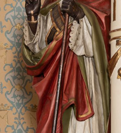 Zdjęcie nr 8: Nastawa ołtarzowa uzyskała charakter jednoosiowej, jednokondygnacyjnej przestrzennej struktury architektonicznej ze zwieńczeniem. Drewniany stipes ołtarzowy przyjął kształt zwężającego się ku dołowi sarkofagu wspierającego mensę, ustawionego na marmurowym podeście o dwu stopniach. Na mensie na osi ustawiono prostopadłościenne tabernakulum na rzucie trapezu, ujęte po bokach spływami wolutowym podtrzymującymi proste belkowanie wyłamane na osi podpór. Drzwiczki do tabernakulum uzyskały kształt stojącego prostokąta zamkniętego u góry łukiem nadwieszonym z uskokiem. W ich polu ukazano kielich z hostią. Retabulum wykonano na rzucie dwóch koncentrycznych półkoli. Pierwsze, tworzy przyścienna struktura flankowana dwoma esowatymi splotami wolutowymi podtrzymującymi architraw z belkowaniem zdobionym fryzem kostkowym, podtrzymującym w osiach skrajnych dwa wolutowe postumenty przechodzące w zwieńczenie. Zwieńczenie utworzono z płyciny w kształcie leżącego prostokąta o wklęsłych bokach zwieńczone gzymsem koronującym wygiętym w formie nadwieszonego łuku odcinkowego. W polu zwieńczenia umieszczono płaskorzeźbiony kartusz z monogramem maryjnym w czerwonym polu flankowany przez dwa uskrzydlone aniołki. Drugie półkole uzyskano z wysunięcia przed lico nastawy dwóch kolumn wspartych na wysokich, dwupoziomowych postumentach oraz flankujących główne pole obrazowe kondygnacji dwóch pilastrów podtrzymujących półkoliście wygięty architraw z belkowaniem, na końcach którego umieszczono przerwane wolutowe przyczółki faliste z siedzącymi na nich dwoma aniołami podtrzymującymi zawieszoną na osi monumentalną koronę zamknietą. Kolumny i pilastry o korynckich kapitelach i głowicach w dwóch trzecich od góry są kanelowane, a niżej gładkie i zdobione wstęgami z zawieszonymi zwisami owocowymi. Podtrzymujące kolumny postumenty ozdobiono niebieskimi, prostokątnymi płycinami u góry zamkniętymi półkoliście, a u dołu wklęsłymi. Po osiach zewnętrznych do postumentów przylegają konsole zdobione akantowymi wolutami, na których ustawiono figury św. Wojciech i św. Stanisława. Architraw drugiego półkola ozdobiono rytmiczne rozmieszczonymi partiami ornamentu roślinnego, a belkowanie i przyczółki faliste fryzem kostkowym. W polu kondygnacji umieszczono pole obrazowe w formie stojącego prostokąta zamkniętego od góry łukiem odcinkowym nadwieszonym obramienionym ramą zdobioną ażurową wicią akantową. W polu znajduje się obraz Matki Boskiej z Dzieciątkiem w rzymskim typie Salus Populi Romani, a na zasuwie obraz przedstawiający wybór św. Macieja na apostoła. Strukturę ołtarza pomalowano w tonacji ciemnej kości słoniowej. Kolumny, profile oraz ornamenty zostały wyzłocone. Rzeźby św. Wojciech i św. Stanisława uzyskały naturalistyczną polichromię podobnie jak anioły podtrzymujące koronę.  