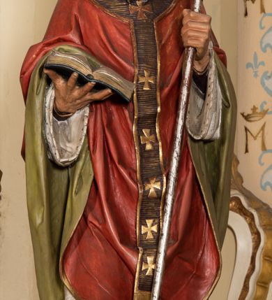 Zdjęcie nr 10: Nastawa ołtarzowa uzyskała charakter jednoosiowej, jednokondygnacyjnej przestrzennej struktury architektonicznej ze zwieńczeniem. Drewniany stipes ołtarzowy przyjął kształt zwężającego się ku dołowi sarkofagu wspierającego mensę, ustawionego na marmurowym podeście o dwu stopniach. Na mensie na osi ustawiono prostopadłościenne tabernakulum na rzucie trapezu, ujęte po bokach spływami wolutowym podtrzymującymi proste belkowanie wyłamane na osi podpór. Drzwiczki do tabernakulum uzyskały kształt stojącego prostokąta zamkniętego u góry łukiem nadwieszonym z uskokiem. W ich polu ukazano kielich z hostią. Retabulum wykonano na rzucie dwóch koncentrycznych półkoli. Pierwsze, tworzy przyścienna struktura flankowana dwoma esowatymi splotami wolutowymi podtrzymującymi architraw z belkowaniem zdobionym fryzem kostkowym, podtrzymującym w osiach skrajnych dwa wolutowe postumenty przechodzące w zwieńczenie. Zwieńczenie utworzono z płyciny w kształcie leżącego prostokąta o wklęsłych bokach zwieńczone gzymsem koronującym wygiętym w formie nadwieszonego łuku odcinkowego. W polu zwieńczenia umieszczono płaskorzeźbiony kartusz z monogramem maryjnym w czerwonym polu flankowany przez dwa uskrzydlone aniołki. Drugie półkole uzyskano z wysunięcia przed lico nastawy dwóch kolumn wspartych na wysokich, dwupoziomowych postumentach oraz flankujących główne pole obrazowe kondygnacji dwóch pilastrów podtrzymujących półkoliście wygięty architraw z belkowaniem, na końcach którego umieszczono przerwane wolutowe przyczółki faliste z siedzącymi na nich dwoma aniołami podtrzymującymi zawieszoną na osi monumentalną koronę zamknietą. Kolumny i pilastry o korynckich kapitelach i głowicach w dwóch trzecich od góry są kanelowane, a niżej gładkie i zdobione wstęgami z zawieszonymi zwisami owocowymi. Podtrzymujące kolumny postumenty ozdobiono niebieskimi, prostokątnymi płycinami u góry zamkniętymi półkoliście, a u dołu wklęsłymi. Po osiach zewnętrznych do postumentów przylegają konsole zdobione akantowymi wolutami, na których ustawiono figury św. Wojciech i św. Stanisława. Architraw drugiego półkola ozdobiono rytmiczne rozmieszczonymi partiami ornamentu roślinnego, a belkowanie i przyczółki faliste fryzem kostkowym. W polu kondygnacji umieszczono pole obrazowe w formie stojącego prostokąta zamkniętego od góry łukiem odcinkowym nadwieszonym obramienionym ramą zdobioną ażurową wicią akantową. W polu znajduje się obraz Matki Boskiej z Dzieciątkiem w rzymskim typie Salus Populi Romani, a na zasuwie obraz przedstawiający wybór św. Macieja na apostoła. Strukturę ołtarza pomalowano w tonacji ciemnej kości słoniowej. Kolumny, profile oraz ornamenty zostały wyzłocone. Rzeźby św. Wojciech i św. Stanisława uzyskały naturalistyczną polichromię podobnie jak anioły podtrzymujące koronę.  