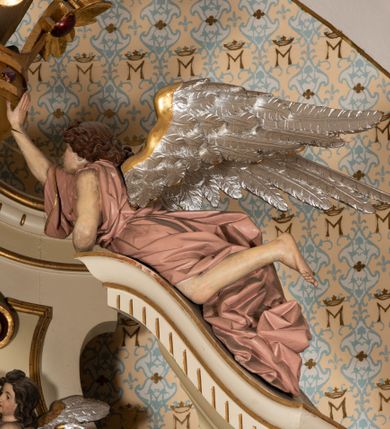 Zdjęcie nr 15: Nastawa ołtarzowa uzyskała charakter jednoosiowej, jednokondygnacyjnej przestrzennej struktury architektonicznej ze zwieńczeniem. Drewniany stipes ołtarzowy przyjął kształt zwężającego się ku dołowi sarkofagu wspierającego mensę, ustawionego na marmurowym podeście o dwu stopniach. Na mensie na osi ustawiono prostopadłościenne tabernakulum na rzucie trapezu, ujęte po bokach spływami wolutowym podtrzymującymi proste belkowanie wyłamane na osi podpór. Drzwiczki do tabernakulum uzyskały kształt stojącego prostokąta zamkniętego u góry łukiem nadwieszonym z uskokiem. W ich polu ukazano kielich z hostią. Retabulum wykonano na rzucie dwóch koncentrycznych półkoli. Pierwsze, tworzy przyścienna struktura flankowana dwoma esowatymi splotami wolutowymi podtrzymującymi architraw z belkowaniem zdobionym fryzem kostkowym, podtrzymującym w osiach skrajnych dwa wolutowe postumenty przechodzące w zwieńczenie. Zwieńczenie utworzono z płyciny w kształcie leżącego prostokąta o wklęsłych bokach zwieńczone gzymsem koronującym wygiętym w formie nadwieszonego łuku odcinkowego. W polu zwieńczenia umieszczono płaskorzeźbiony kartusz z monogramem maryjnym w czerwonym polu flankowany przez dwa uskrzydlone aniołki. Drugie półkole uzyskano z wysunięcia przed lico nastawy dwóch kolumn wspartych na wysokich, dwupoziomowych postumentach oraz flankujących główne pole obrazowe kondygnacji dwóch pilastrów podtrzymujących półkoliście wygięty architraw z belkowaniem, na końcach którego umieszczono przerwane wolutowe przyczółki faliste z siedzącymi na nich dwoma aniołami podtrzymującymi zawieszoną na osi monumentalną koronę zamknietą. Kolumny i pilastry o korynckich kapitelach i głowicach w dwóch trzecich od góry są kanelowane, a niżej gładkie i zdobione wstęgami z zawieszonymi zwisami owocowymi. Podtrzymujące kolumny postumenty ozdobiono niebieskimi, prostokątnymi płycinami u góry zamkniętymi półkoliście, a u dołu wklęsłymi. Po osiach zewnętrznych do postumentów przylegają konsole zdobione akantowymi wolutami, na których ustawiono figury św. Wojciech i św. Stanisława. Architraw drugiego półkola ozdobiono rytmiczne rozmieszczonymi partiami ornamentu roślinnego, a belkowanie i przyczółki faliste fryzem kostkowym. W polu kondygnacji umieszczono pole obrazowe w formie stojącego prostokąta zamkniętego od góry łukiem odcinkowym nadwieszonym obramienionym ramą zdobioną ażurową wicią akantową. W polu znajduje się obraz Matki Boskiej z Dzieciątkiem w rzymskim typie Salus Populi Romani, a na zasuwie obraz przedstawiający wybór św. Macieja na apostoła. Strukturę ołtarza pomalowano w tonacji ciemnej kości słoniowej. Kolumny, profile oraz ornamenty zostały wyzłocone. Rzeźby św. Wojciech i św. Stanisława uzyskały naturalistyczną polichromię podobnie jak anioły podtrzymujące koronę.  