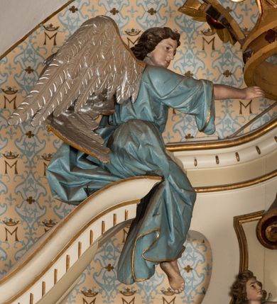 Zdjęcie nr 12: Nastawa ołtarzowa uzyskała charakter jednoosiowej, jednokondygnacyjnej przestrzennej struktury architektonicznej ze zwieńczeniem. Drewniany stipes ołtarzowy przyjął kształt zwężającego się ku dołowi sarkofagu wspierającego mensę, ustawionego na marmurowym podeście o dwu stopniach. Na mensie na osi ustawiono prostopadłościenne tabernakulum na rzucie trapezu, ujęte po bokach spływami wolutowym podtrzymującymi proste belkowanie wyłamane na osi podpór. Drzwiczki do tabernakulum uzyskały kształt stojącego prostokąta zamkniętego u góry łukiem nadwieszonym z uskokiem. W ich polu ukazano kielich z hostią. Retabulum wykonano na rzucie dwóch koncentrycznych półkoli. Pierwsze, tworzy przyścienna struktura flankowana dwoma esowatymi splotami wolutowymi podtrzymującymi architraw z belkowaniem zdobionym fryzem kostkowym, podtrzymującym w osiach skrajnych dwa wolutowe postumenty przechodzące w zwieńczenie. Zwieńczenie utworzono z płyciny w kształcie leżącego prostokąta o wklęsłych bokach zwieńczone gzymsem koronującym wygiętym w formie nadwieszonego łuku odcinkowego. W polu zwieńczenia umieszczono płaskorzeźbiony kartusz z monogramem maryjnym w czerwonym polu flankowany przez dwa uskrzydlone aniołki. Drugie półkole uzyskano z wysunięcia przed lico nastawy dwóch kolumn wspartych na wysokich, dwupoziomowych postumentach oraz flankujących główne pole obrazowe kondygnacji dwóch pilastrów podtrzymujących półkoliście wygięty architraw z belkowaniem, na końcach którego umieszczono przerwane wolutowe przyczółki faliste z siedzącymi na nich dwoma aniołami podtrzymującymi zawieszoną na osi monumentalną koronę zamknietą. Kolumny i pilastry o korynckich kapitelach i głowicach w dwóch trzecich od góry są kanelowane, a niżej gładkie i zdobione wstęgami z zawieszonymi zwisami owocowymi. Podtrzymujące kolumny postumenty ozdobiono niebieskimi, prostokątnymi płycinami u góry zamkniętymi półkoliście, a u dołu wklęsłymi. Po osiach zewnętrznych do postumentów przylegają konsole zdobione akantowymi wolutami, na których ustawiono figury św. Wojciech i św. Stanisława. Architraw drugiego półkola ozdobiono rytmiczne rozmieszczonymi partiami ornamentu roślinnego, a belkowanie i przyczółki faliste fryzem kostkowym. W polu kondygnacji umieszczono pole obrazowe w formie stojącego prostokąta zamkniętego od góry łukiem odcinkowym nadwieszonym obramienionym ramą zdobioną ażurową wicią akantową. W polu znajduje się obraz Matki Boskiej z Dzieciątkiem w rzymskim typie Salus Populi Romani, a na zasuwie obraz przedstawiający wybór św. Macieja na apostoła. Strukturę ołtarza pomalowano w tonacji ciemnej kości słoniowej. Kolumny, profile oraz ornamenty zostały wyzłocone. Rzeźby św. Wojciech i św. Stanisława uzyskały naturalistyczną polichromię podobnie jak anioły podtrzymujące koronę.  