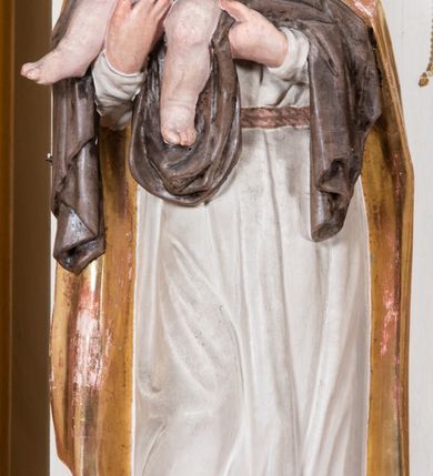 Zdjęcie nr 7: Nastawa ołtarzowa uzyskała charakter przyściennego retabulum jednoosiowego, jednokondygnacyjnego ze zwieńczeniem. Drewniany stipes ołtarzowy przyjął kształt zwężającego się ku dołowi sarkofagu ustawionego na jednostopniowym podeście. Na mensie na osi ustawiono prostopadłościenne tabernakulum obite blachą w formie skrzynki. Drzwiczki do tabernakulum ozdobiono puncowanym krzyżem. Kondygnację nastawy ujmują dwa filary o trzonach zdobionych u góry wolutowymi konsolami i zawieszonymi na taśmie girlandami roślinno-kwiatowymi oraz dwie smukłe kolumny z kapitelami korynckimi, wsparte na wklęsło-wypukłym cokole przerwanym na szerokość pola obrazowego na osi. Cokół artykułują płyciny dekorowane czworobocznym ornamentem roślinnym. Na tle filarów ustawiono rzeźby św. Stanisława Kostki oraz św. Dominika. Pomiędzy filarami widoczne jest prostokątne pole obrazowe ujęte profilowaną ramą, w której umieszczono obraz Niepokalanego Poczęcia. Podpory dźwigają wklęsło-wypukłe belkowanie ustawione na wysokim architrawie dekorowanym czworobocznym ornamentem roślinnym. W osiach skrajnych na belkowaniu umieszczono dwie figury siedzących aniołów. Zwieńczenie nastawy uzyskało kształt leżącego prostokąta o wklęsłych bokach przechodzących w spływy wolutowe, podtrzymujących gzyms koronujący w formie nadwieszonego łuku odcinkowego z krzyżem pośrodku. W polu zwieńczenia umieszczono owalny obraz w profilowanej ramie z przedstawieniem św. Karola Boromeusza. Strukturę ołtarza pomalowano w tonacji jasnobeżowej. Kolumny, profile, ornamenty oraz szaty postaci zostały wyzłocone, a skrzydła aniołów wysrebrzone. Figury w partii ciała otrzymały naturalistyczną polichromię.